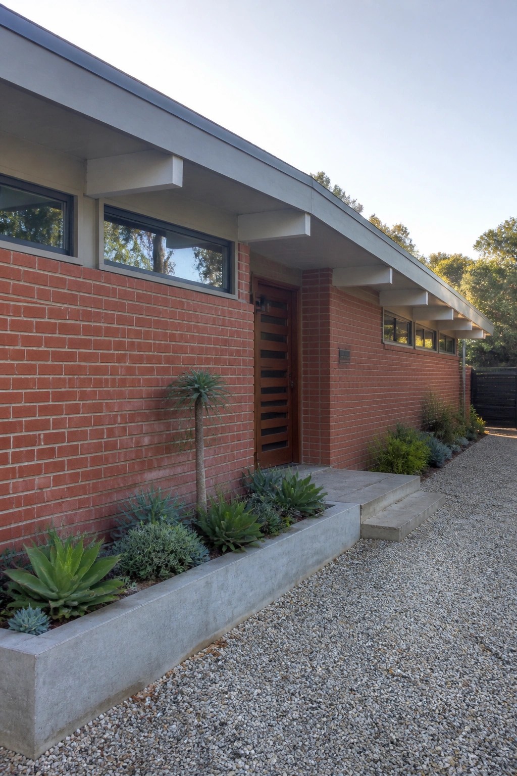 Red brick exterior with light gray concrete planter, steps, and overhangs at the front entry.