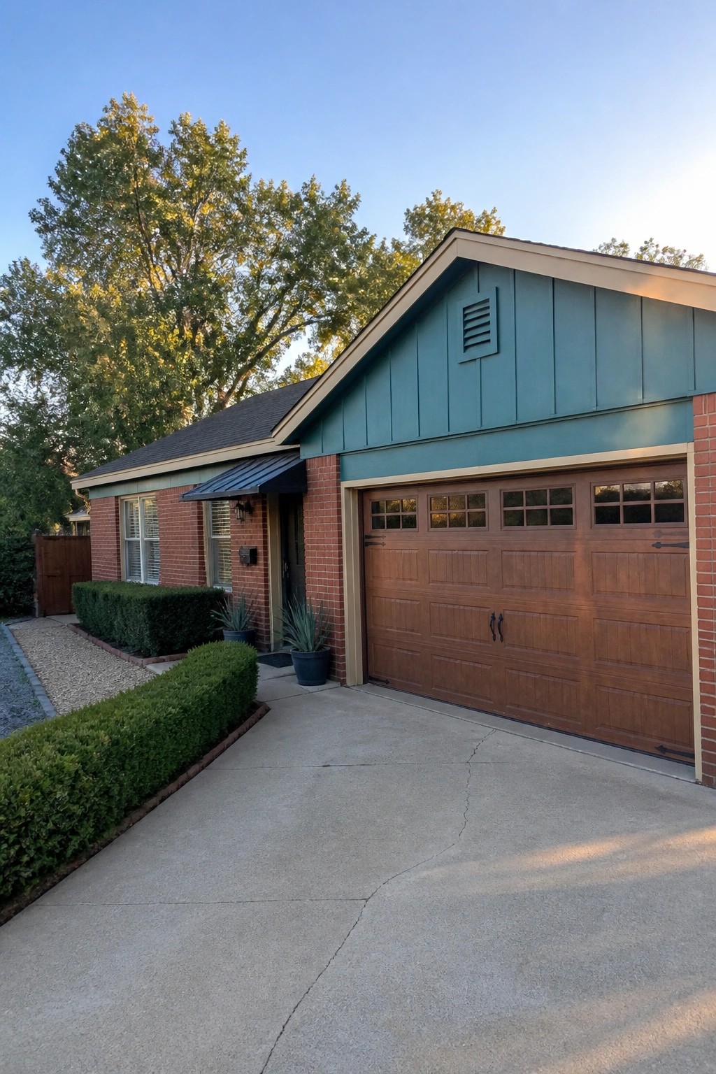 Teal green siding on the gable of a red brick house with a brown garage door.