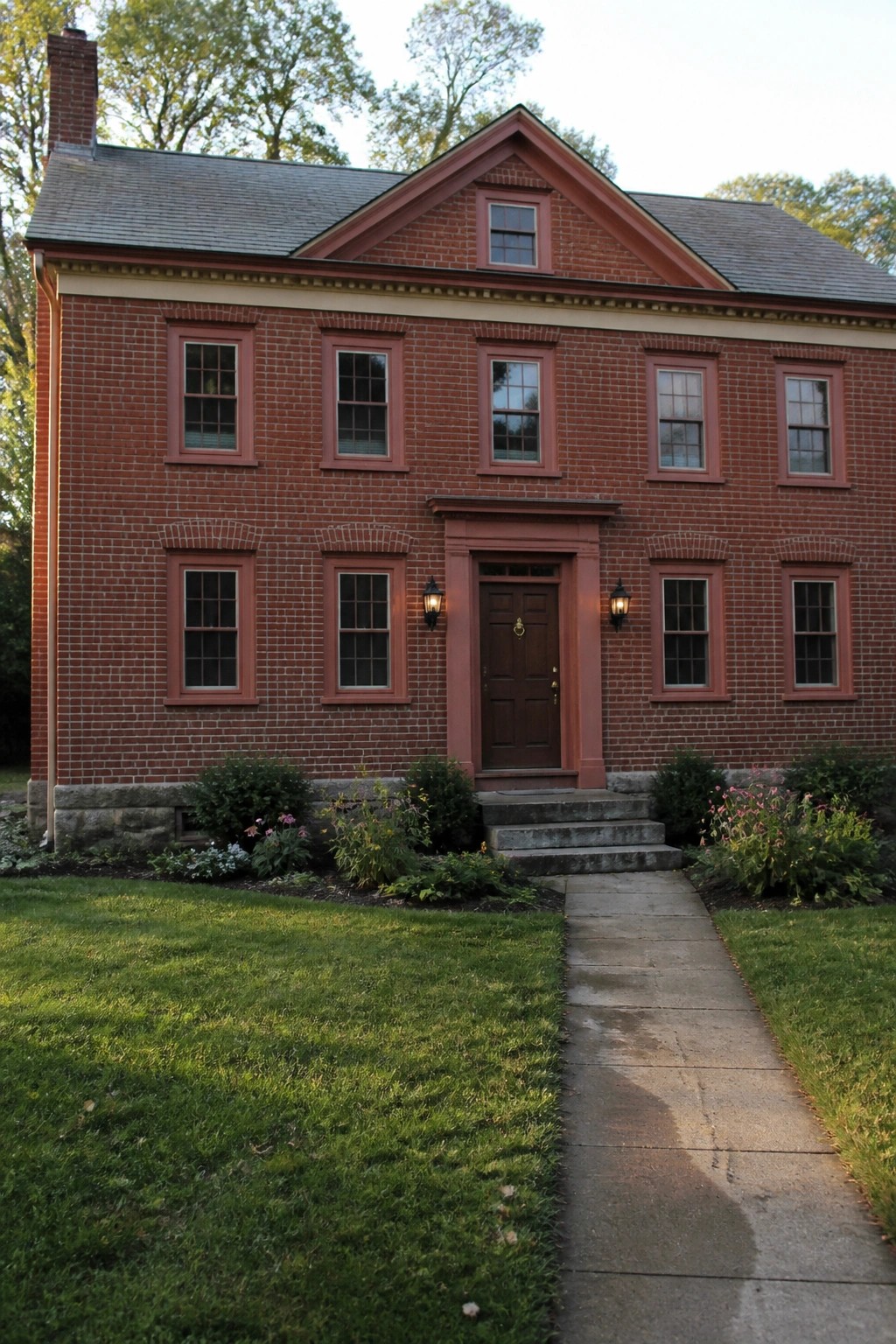 Red brick house exterior with warm red painted trim around windows and entrance.