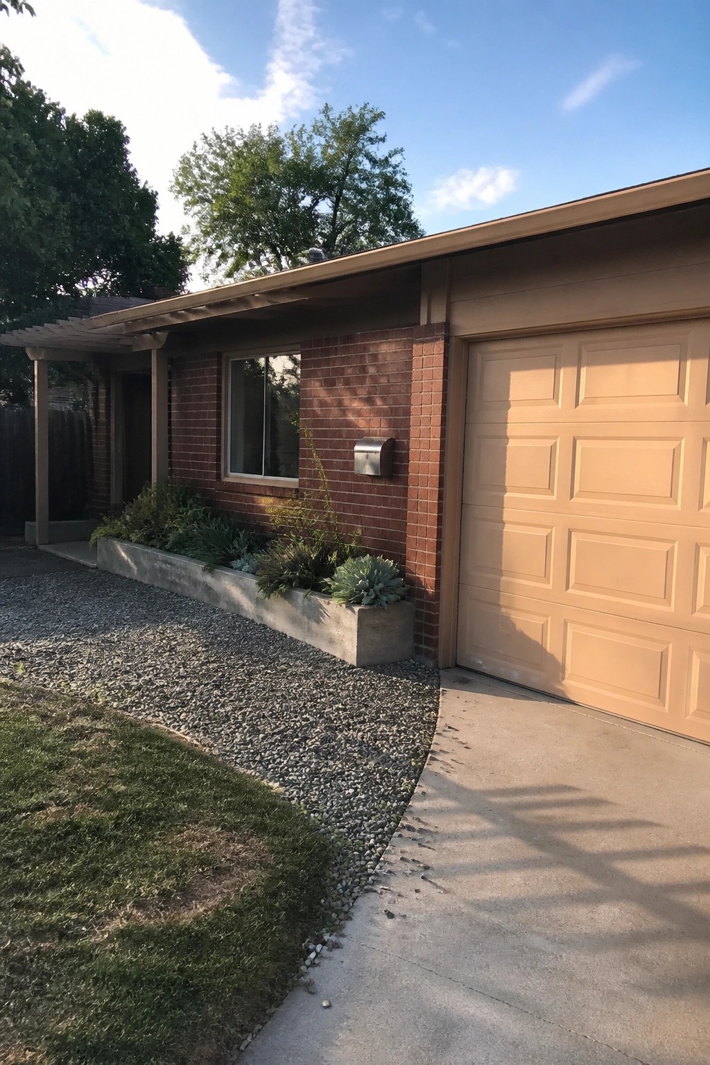 Tan garage door on a red brick house with gravel driveway.