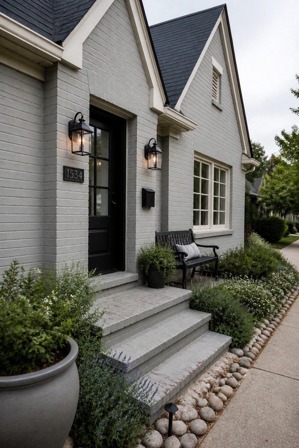 A house exterior painted in soft cool gray siding with a dark roof and black door.