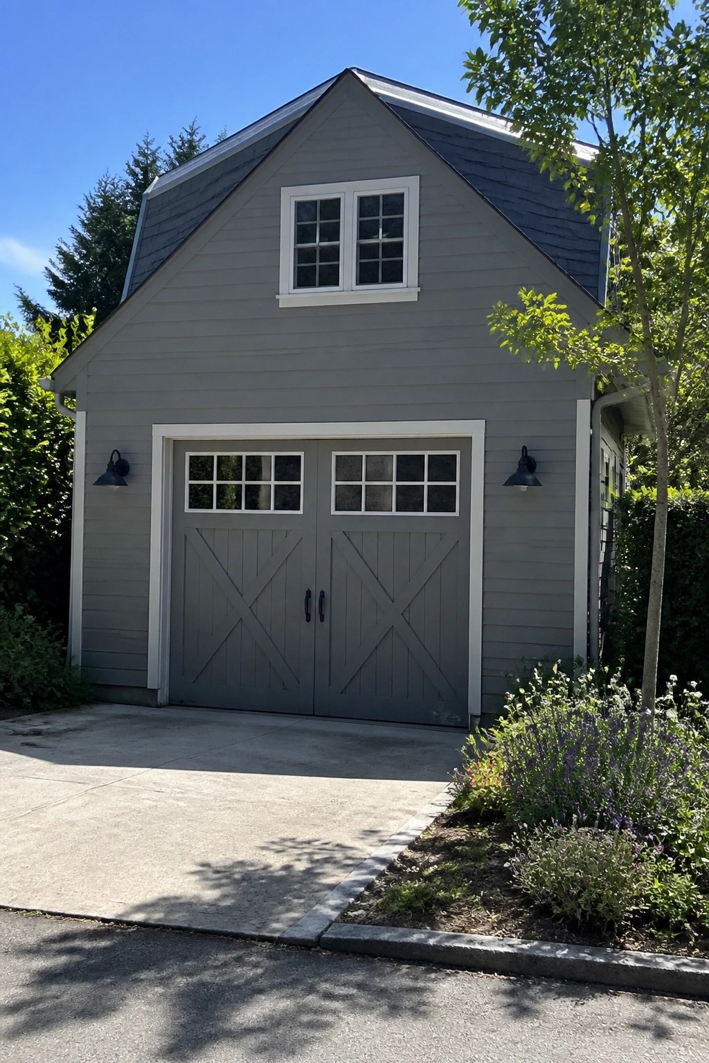 A house exterior painted in soft gray with white trim and a matching garage door under a dark roof.