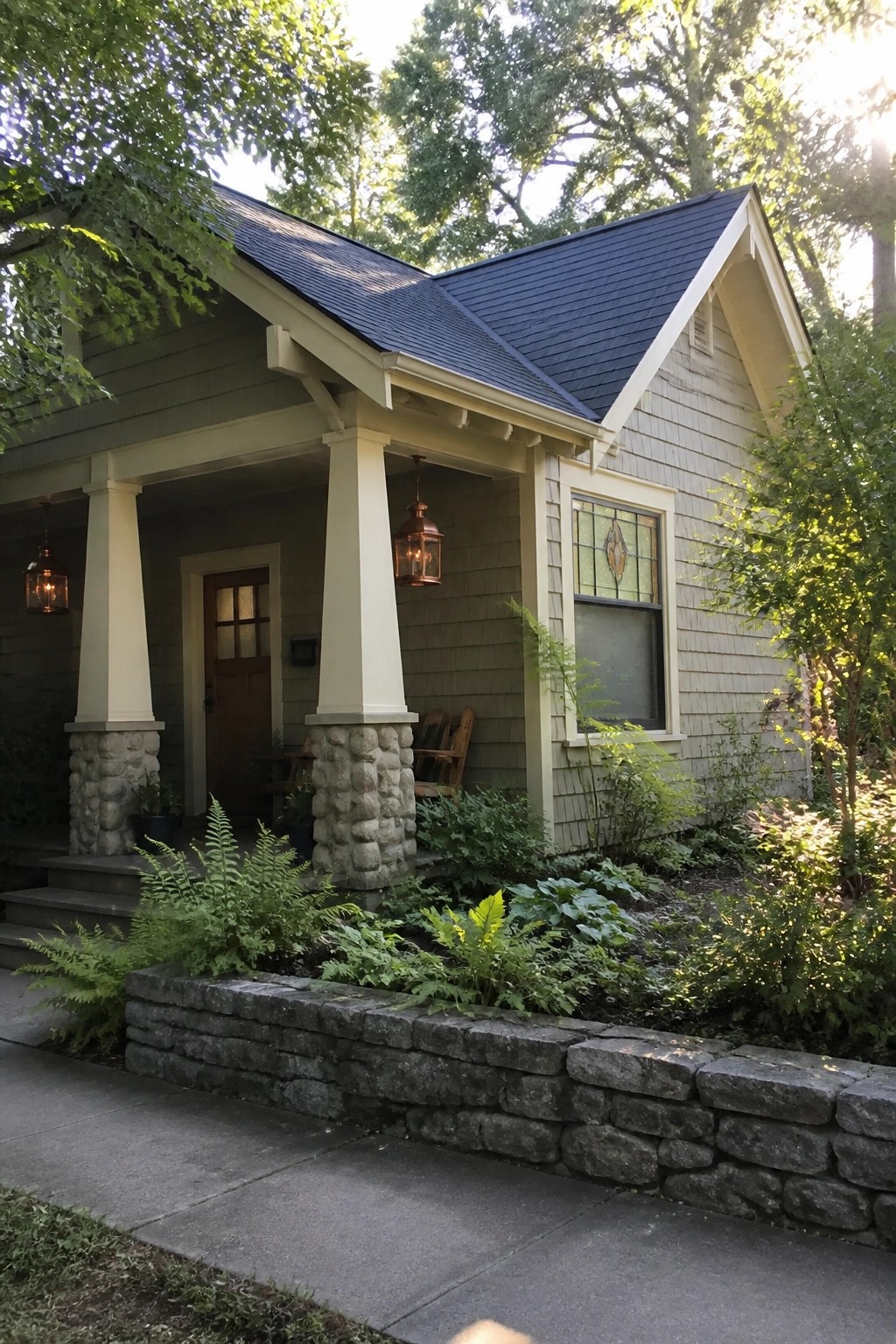 Charming gray house with porch, stone columns, ferns, garden, and dark roof