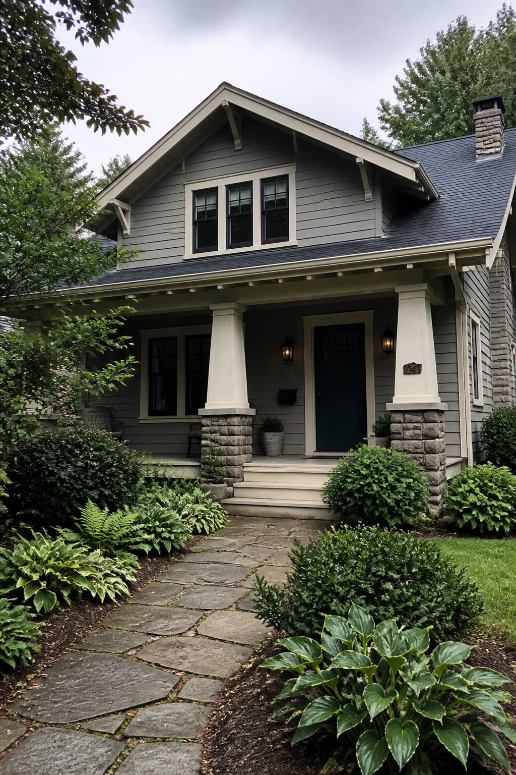 Gray house with blue door, stone porch columns, and lush garden pathway.