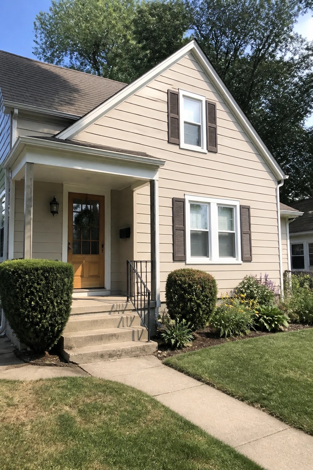 A house exterior painted in warm beige siding with white trim around the porch and windows.
