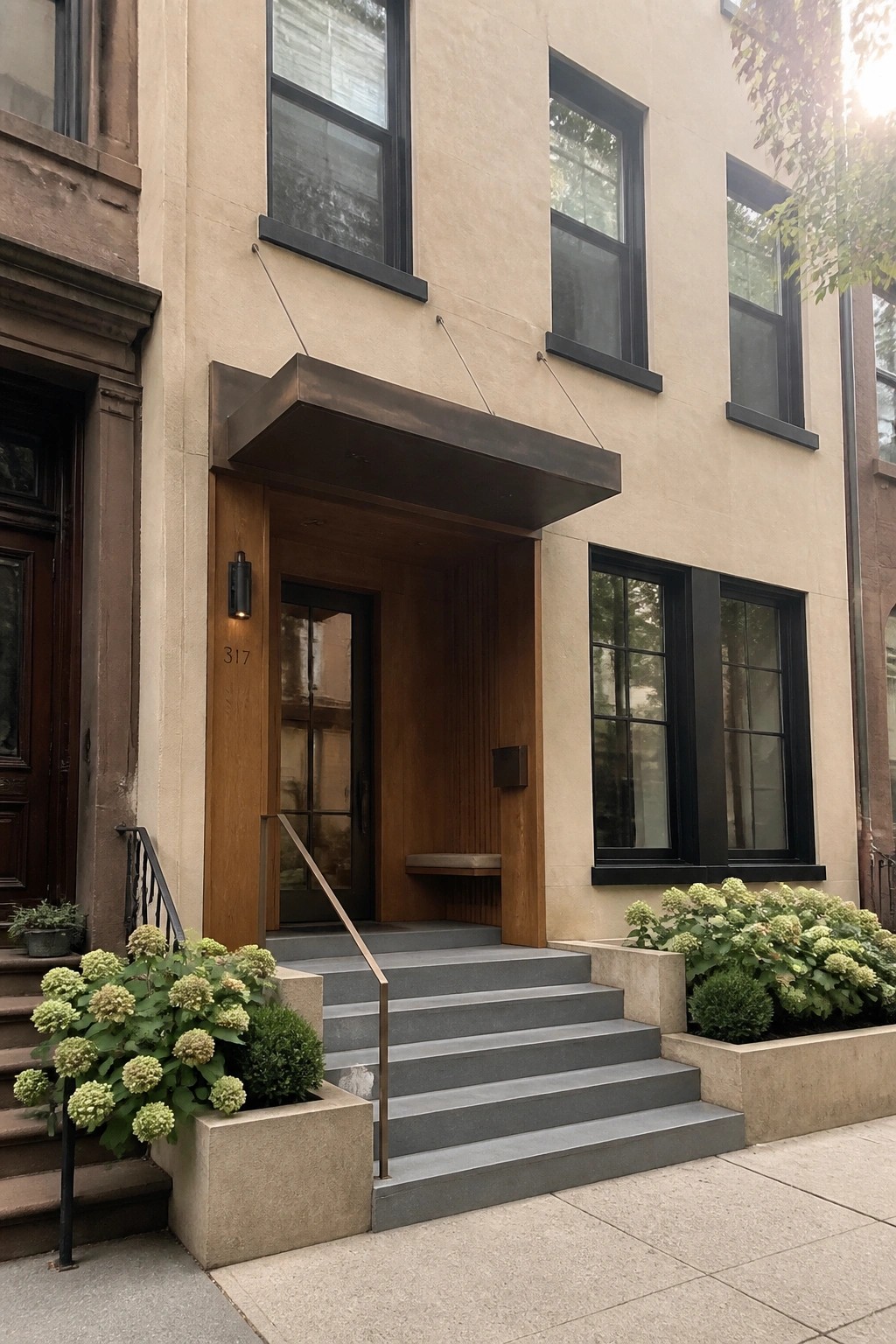 Modern entrance with wooden door 317, gray stairs, metal awning, and hydrangea planters