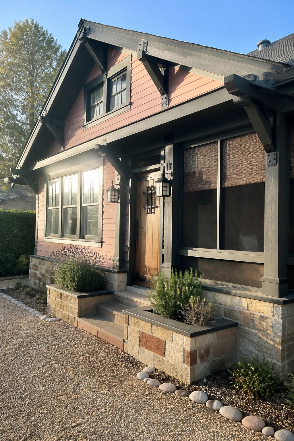 Pink Craftsman house with dark trim, stone foundation, wooden door, and shrub planters.