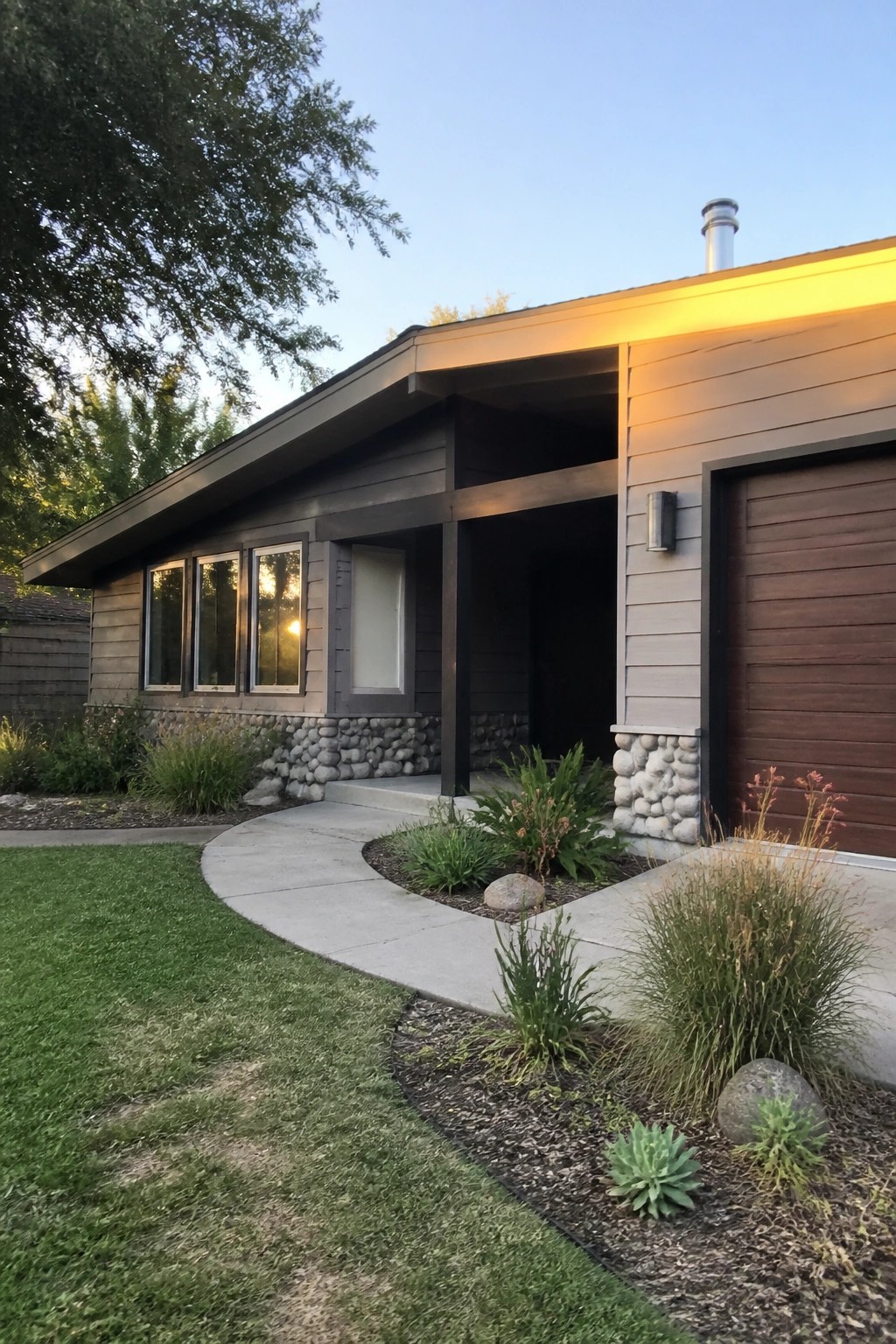 Modern house exterior with dark warm gray siding and stone foundation.