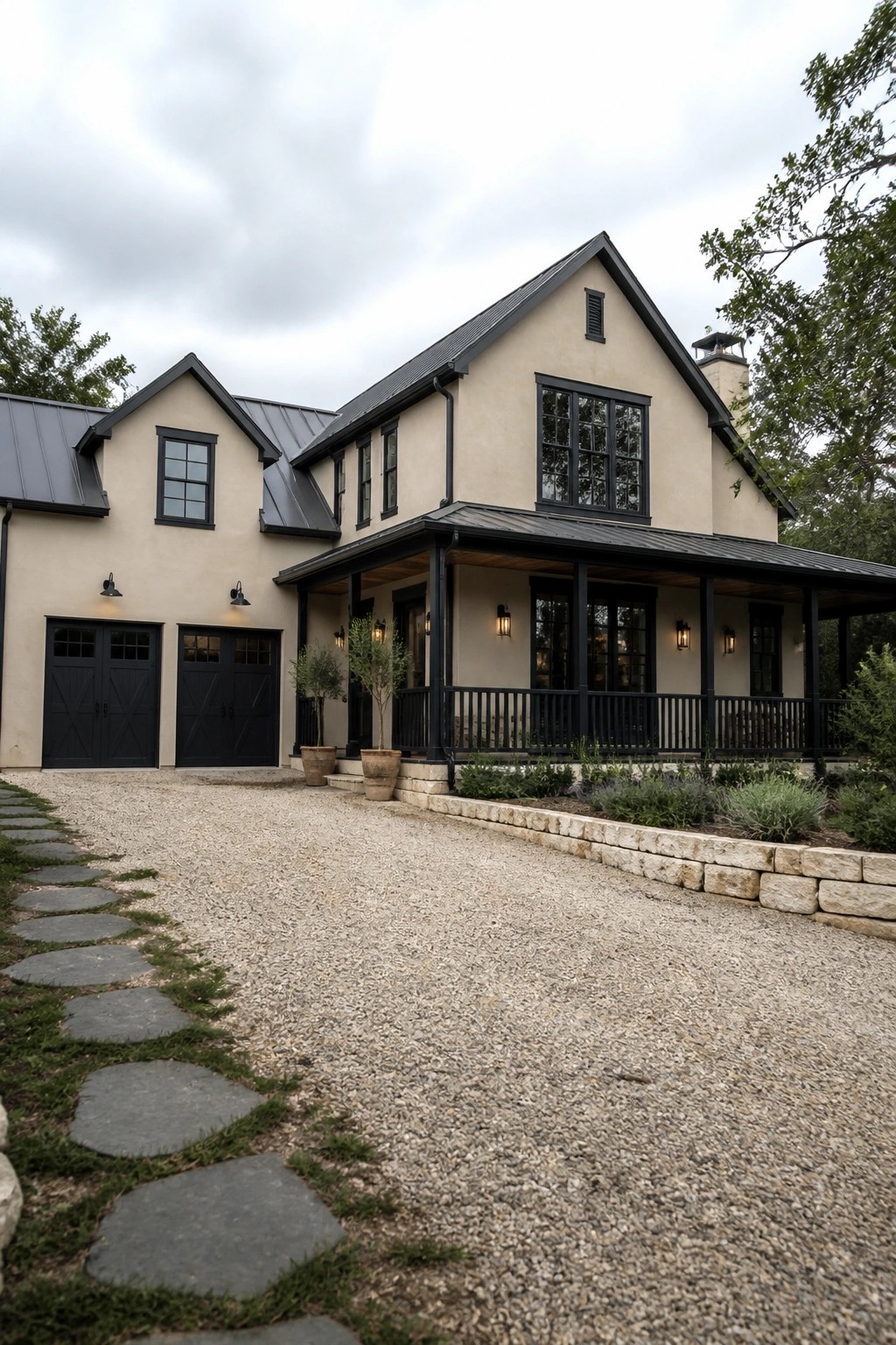 A two-story beige stucco house with black window frames, black garage doors, black porch posts and railing, and a gravel driveway in front.
