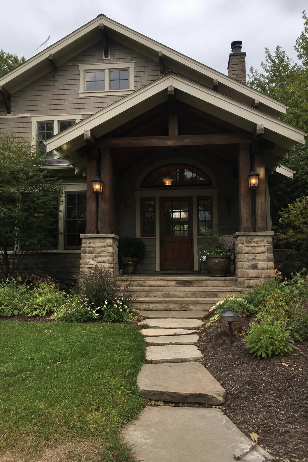 Gray Craftsman house siding with dark wood trim and stone porch columns.