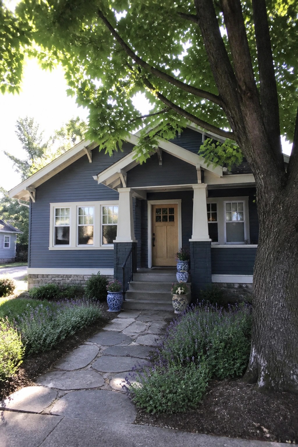 A house exterior painted in dark blue gray siding with white trim and a stone base.