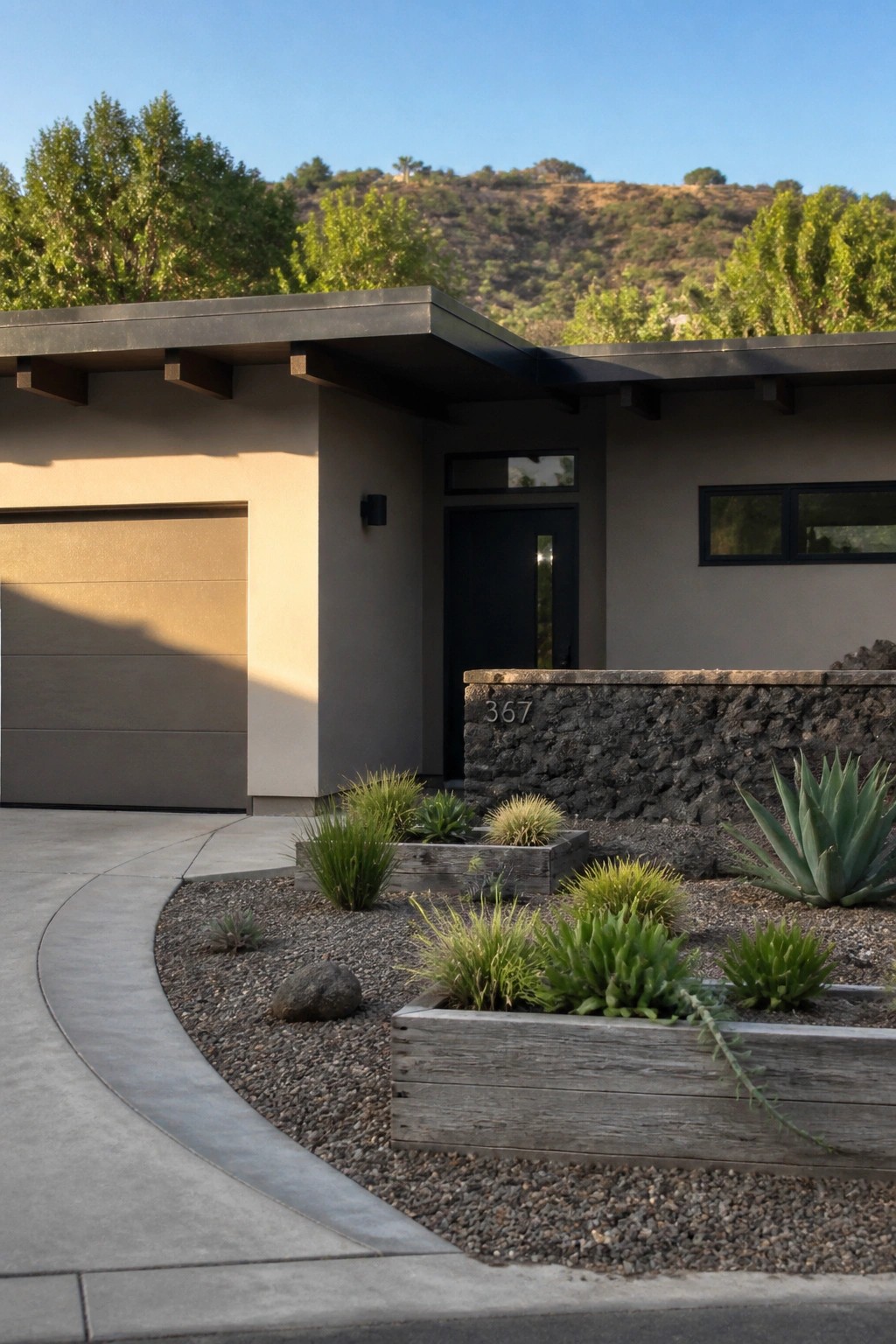 Modern beige house with flat roof, black door, garage, and succulent planters on gravel.