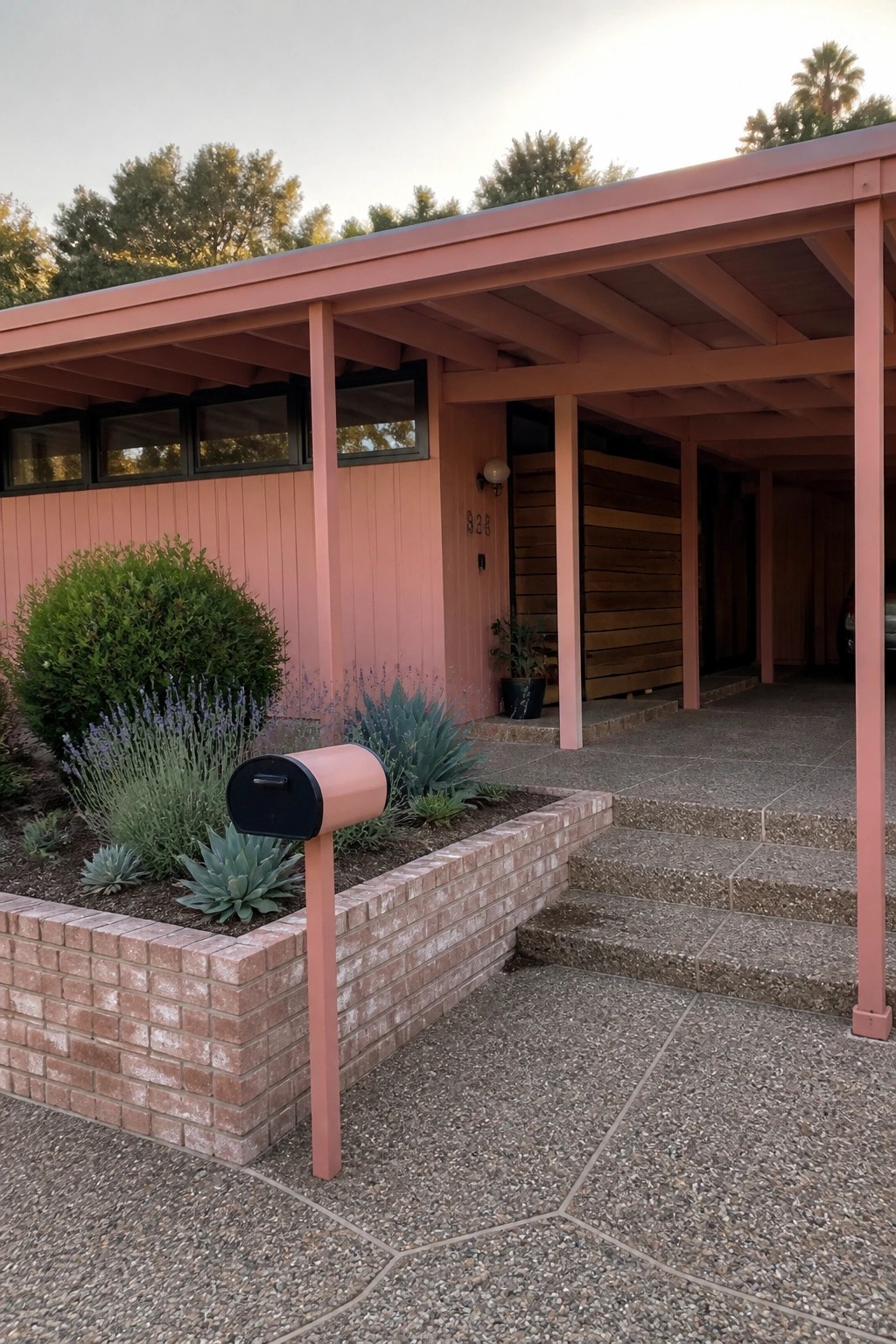 Pink mid-century house with carport, pink mailbox in brick garden bed.