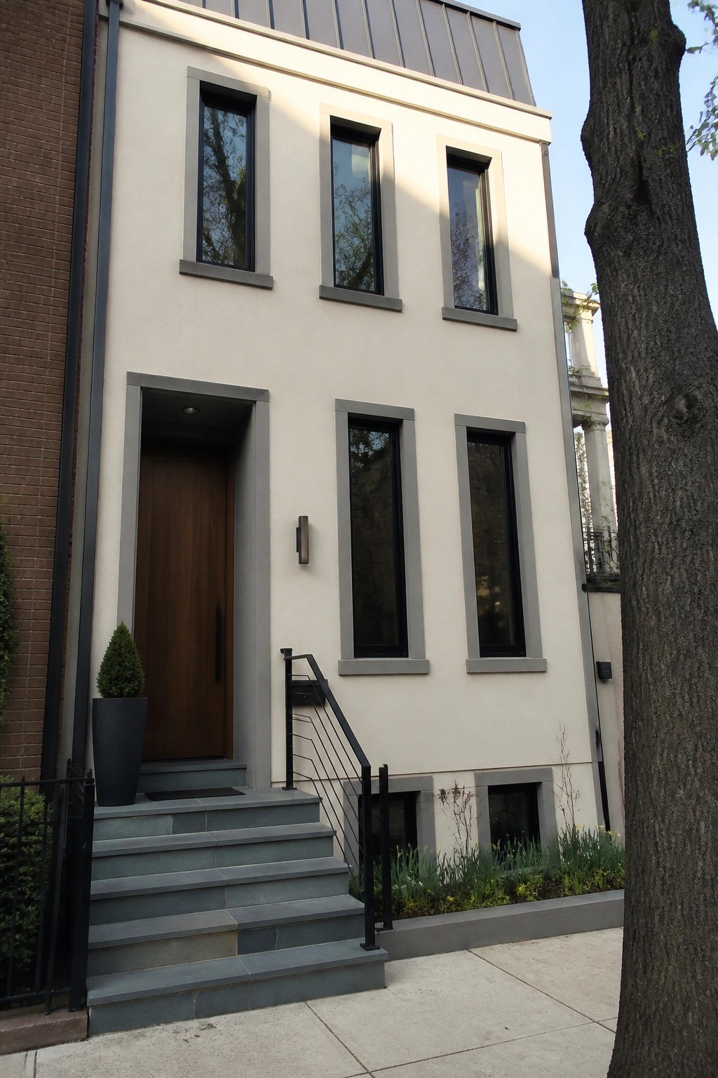 Modern beige townhouse with wooden door, gray windows, and stone steps