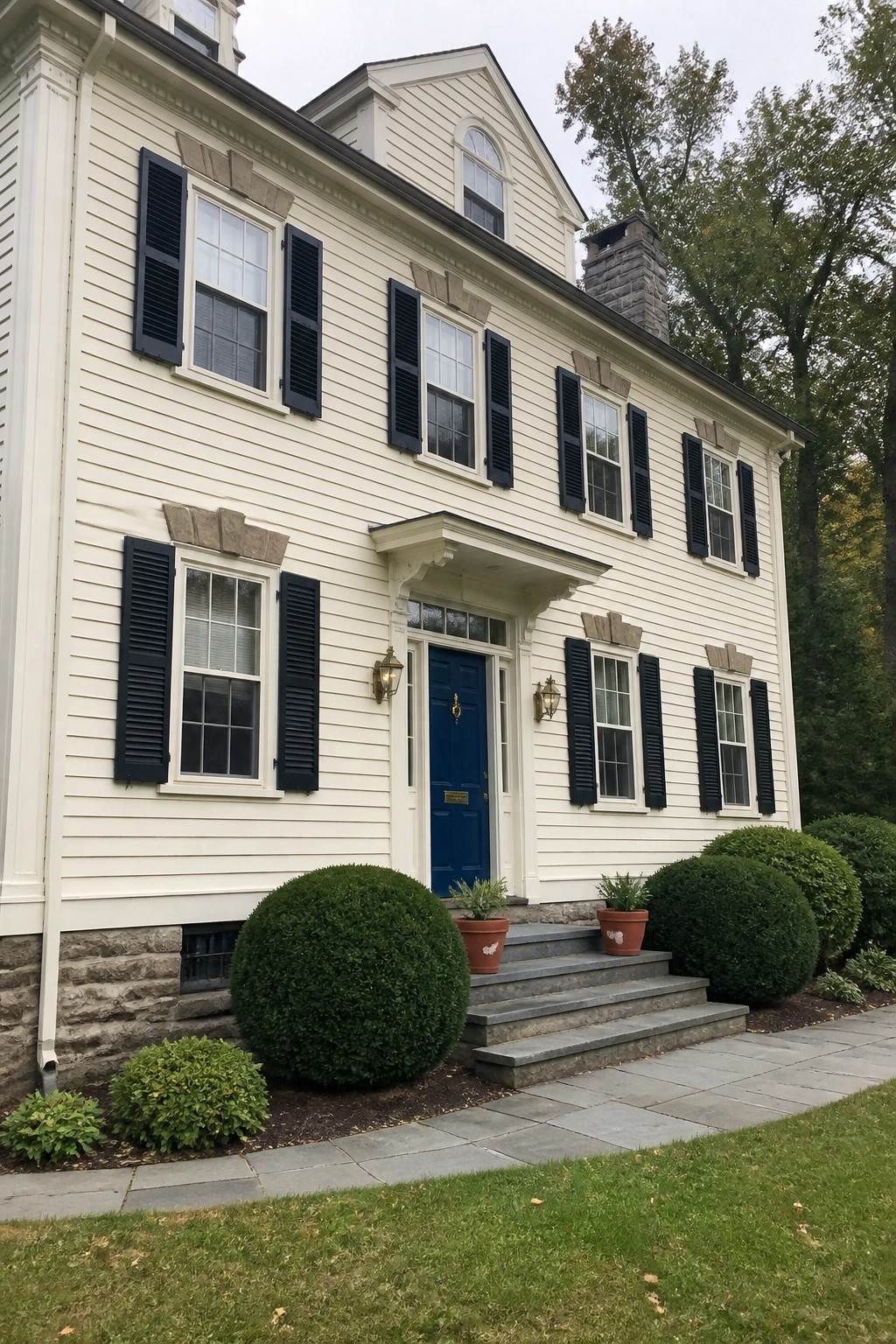 A two-story house with creamy white siding and a stone foundation.