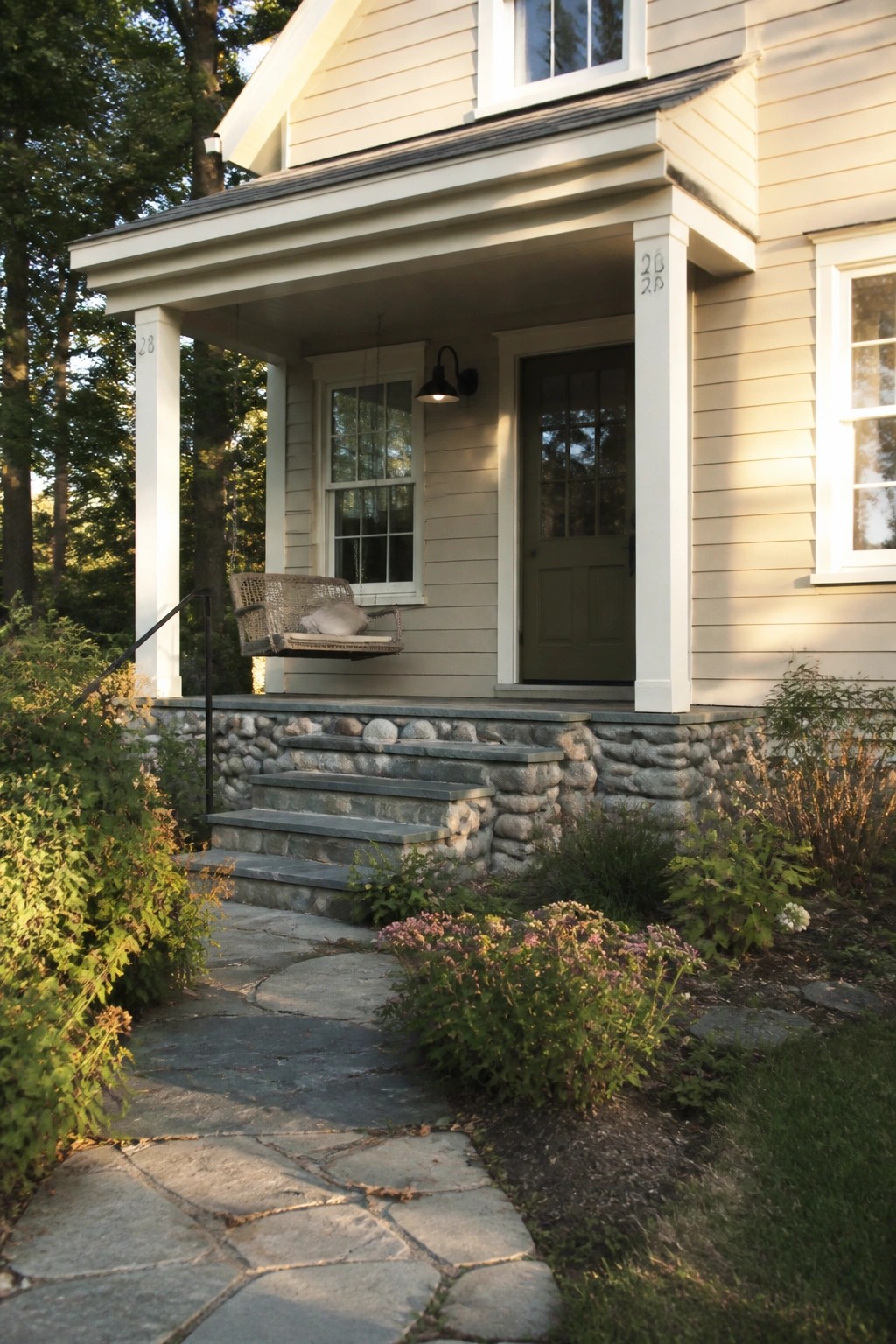 Light warm beige house siding next to a stone porch foundation and steps.