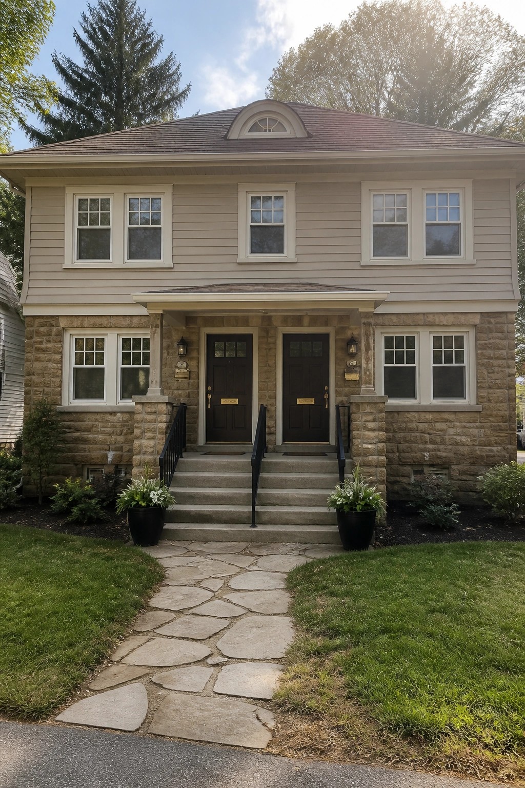 A two-story house with light warm gray siding over a stone foundation.