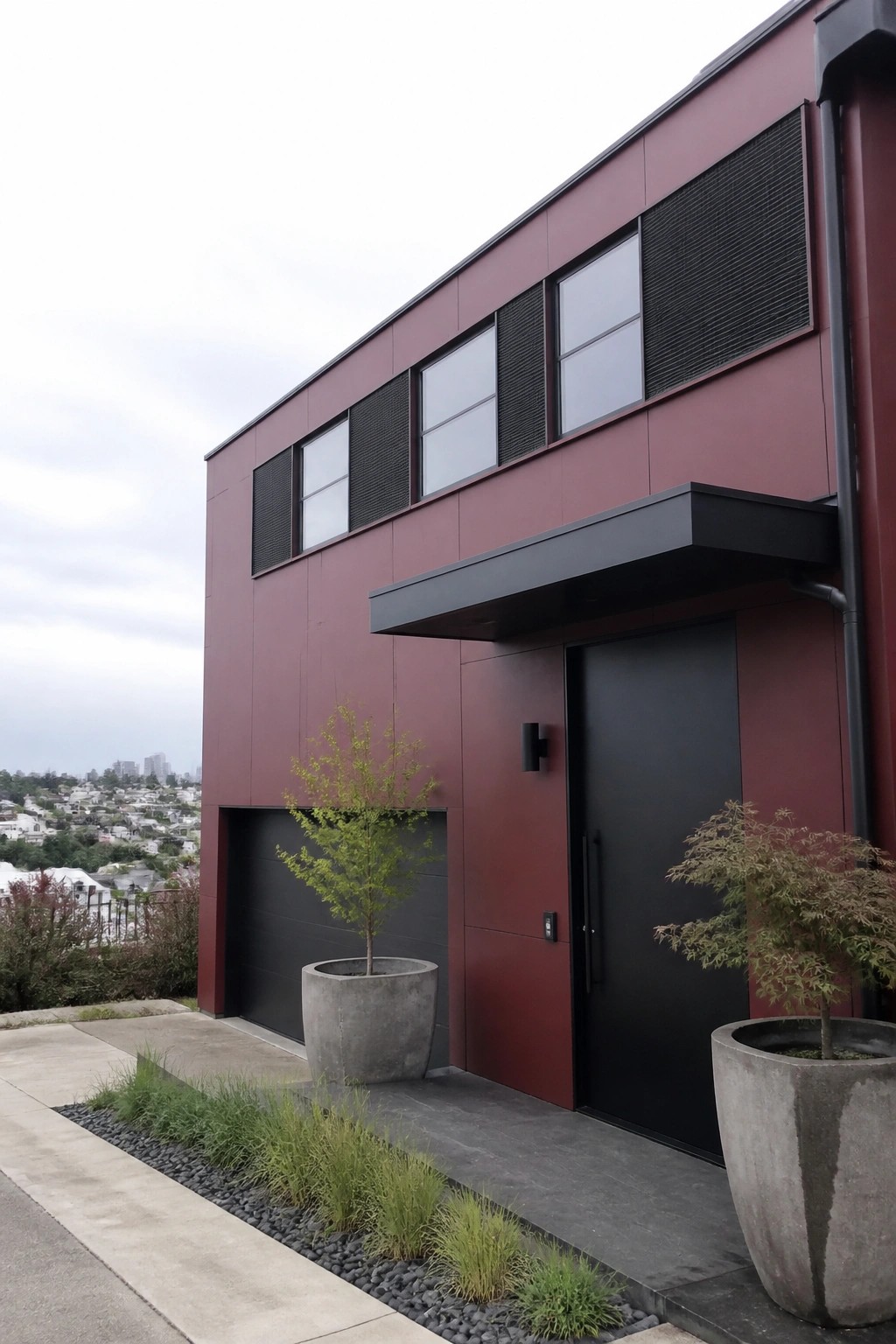 A modern two-story house exterior with deep burgundy siding, a black front door under a black canopy, and black window grilles.