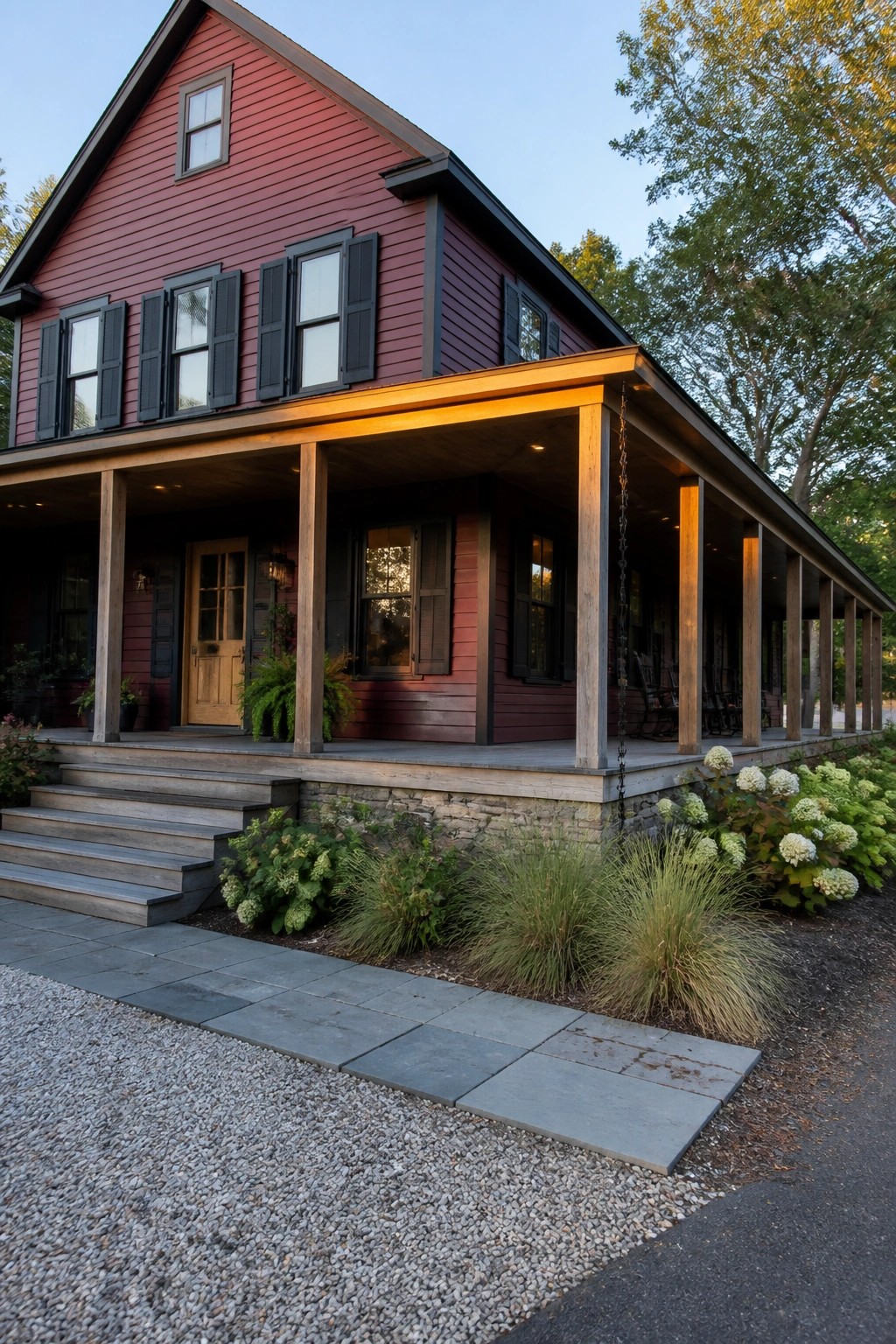 Red two-story house with black shutters, wooden porch, stone steps and landscaping.