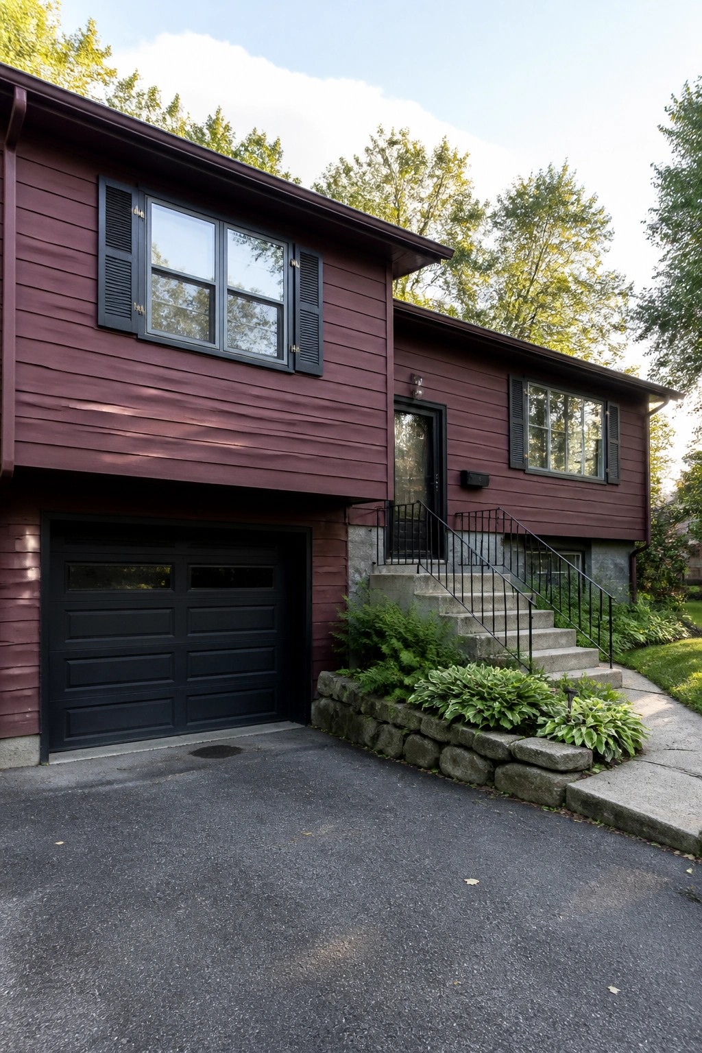 Maroon two-story house with black garage, shutters, door, and entry stairs.