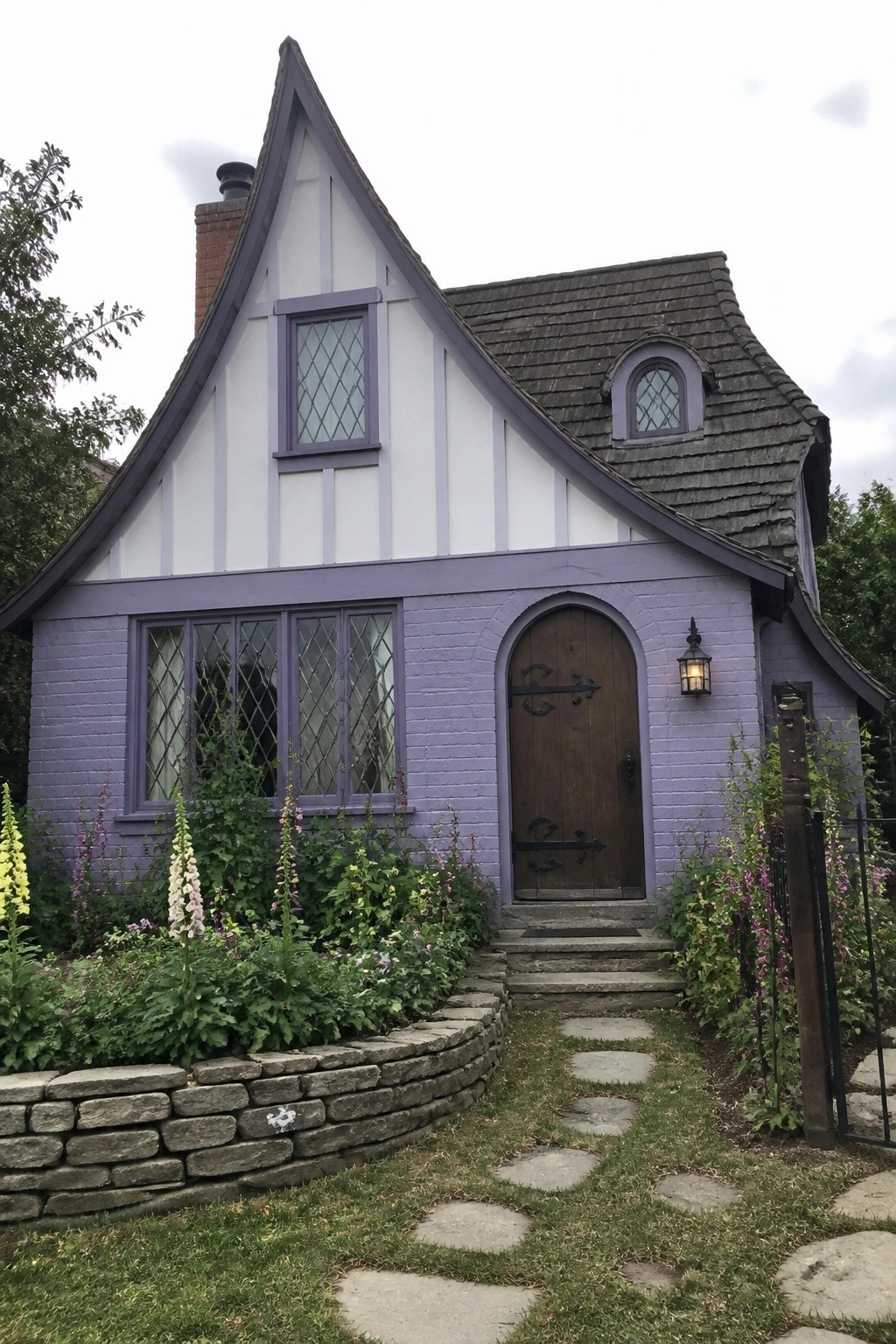 Purple Tudor cottage with white trim, arched door, lattice windows, and flower garden.