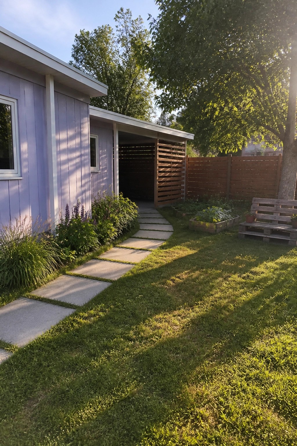 Purple house with stepping stones across lawn to garden and wooden fence.