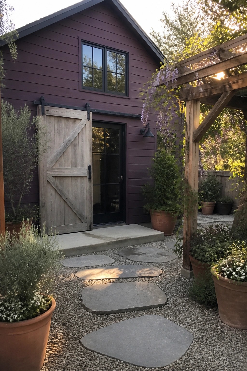 A house exterior with deep purple horizontal lap siding, a wooden sliding barn door, a black entry door, and gravel path with stone stepping stones.