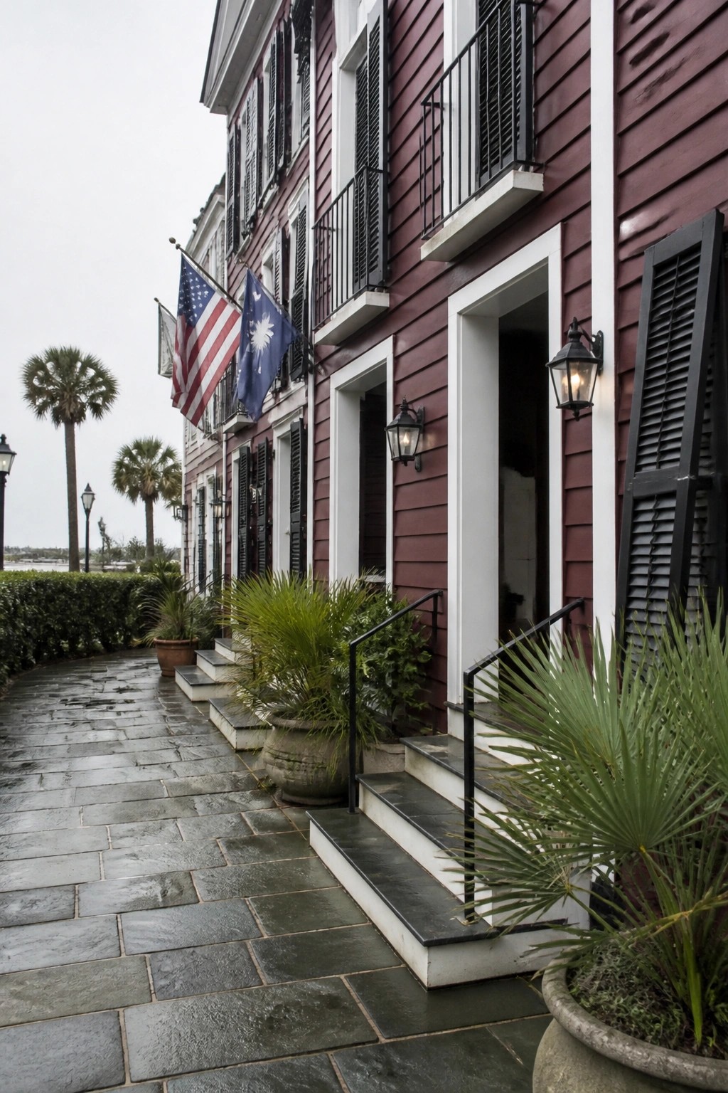 A row of multi-story houses with deep burgundy siding, white window and door trim, black shutters, and stone steps leading to the entrances.