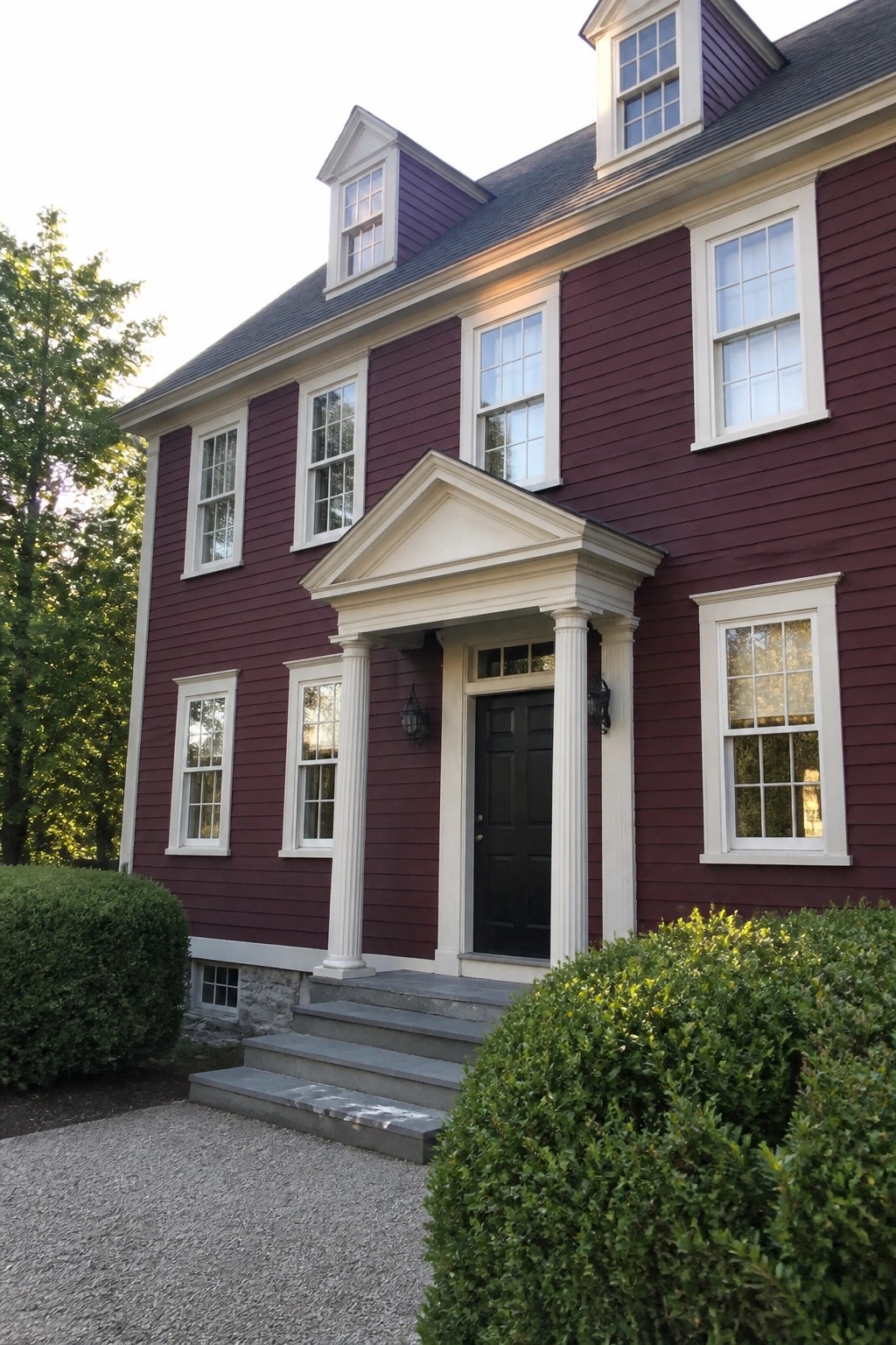Maroon colonial house with white trim, black door, and columned portico.