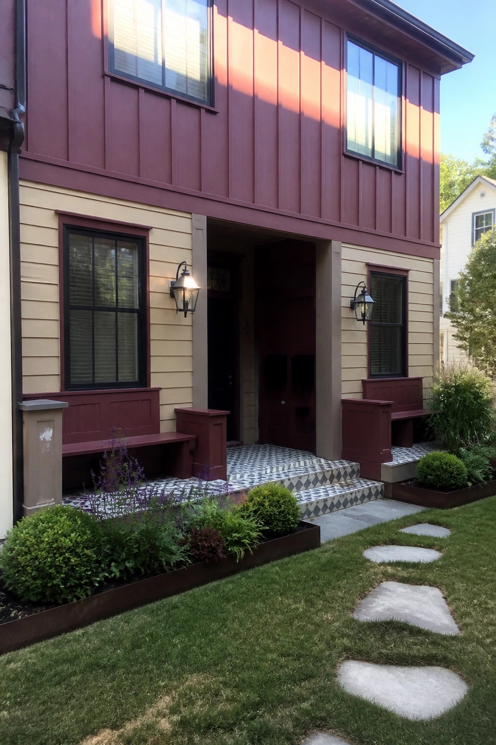 Maroon and beige house with double doors, benches, and stone path
