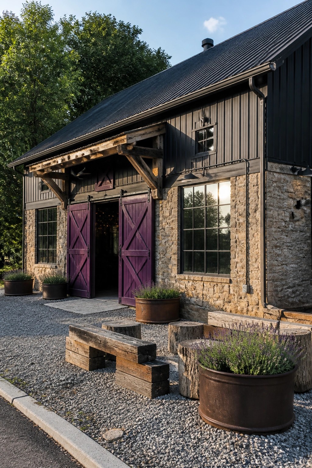 A dark metal-roofed house with stone and vertical siding, featuring large open purple double doors, black trim, and a gravel area with rustic benches and planters.