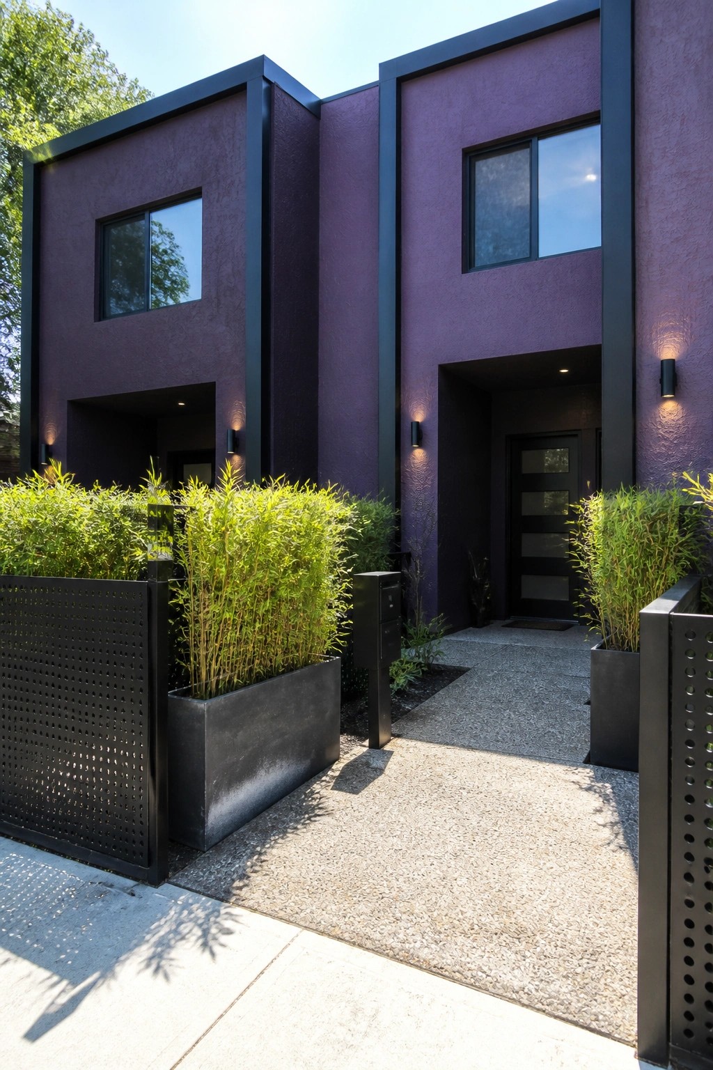 Modern purple building with black trim, windows, door, and green plants in planters.