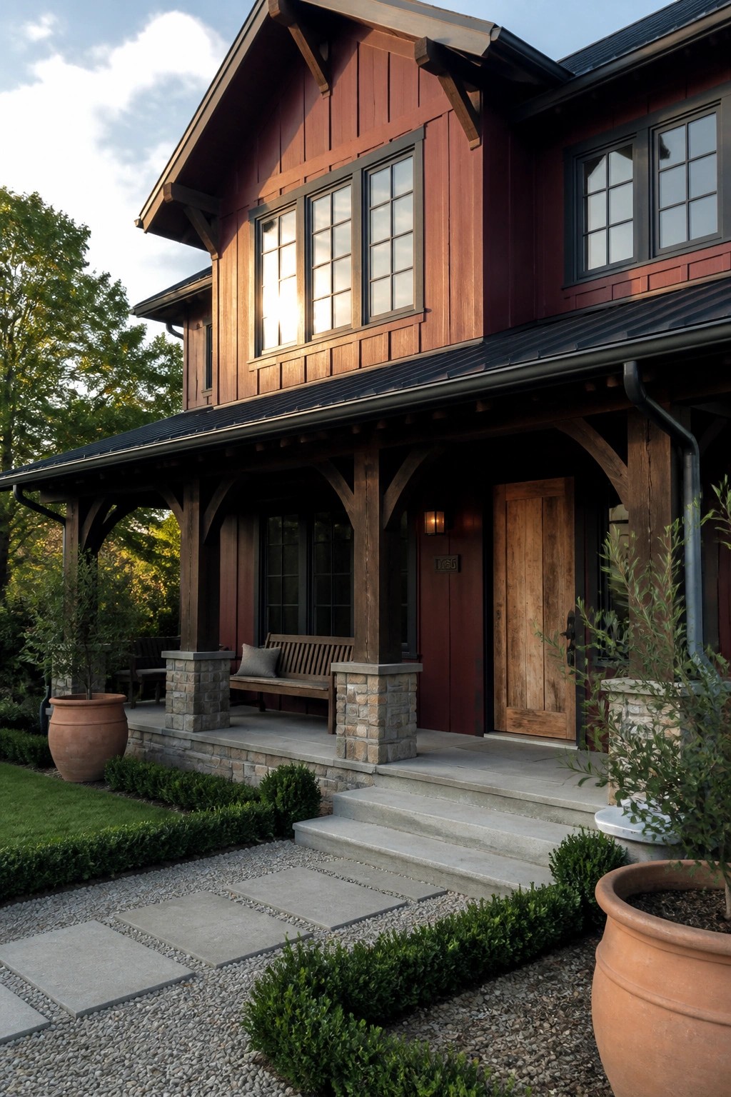 Red wooden Craftsman house with stone porch pillars, steps, and terracotta planters.