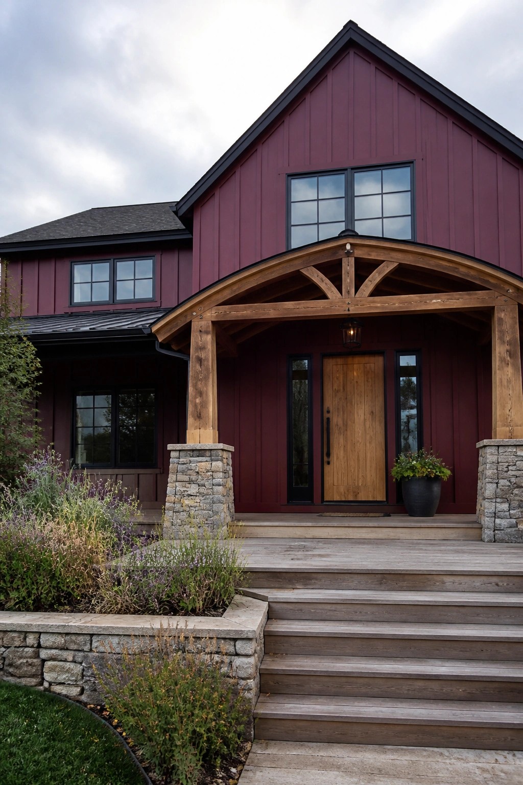 Maroon barn-style house with wooden arched porch, stone pillars, and steps