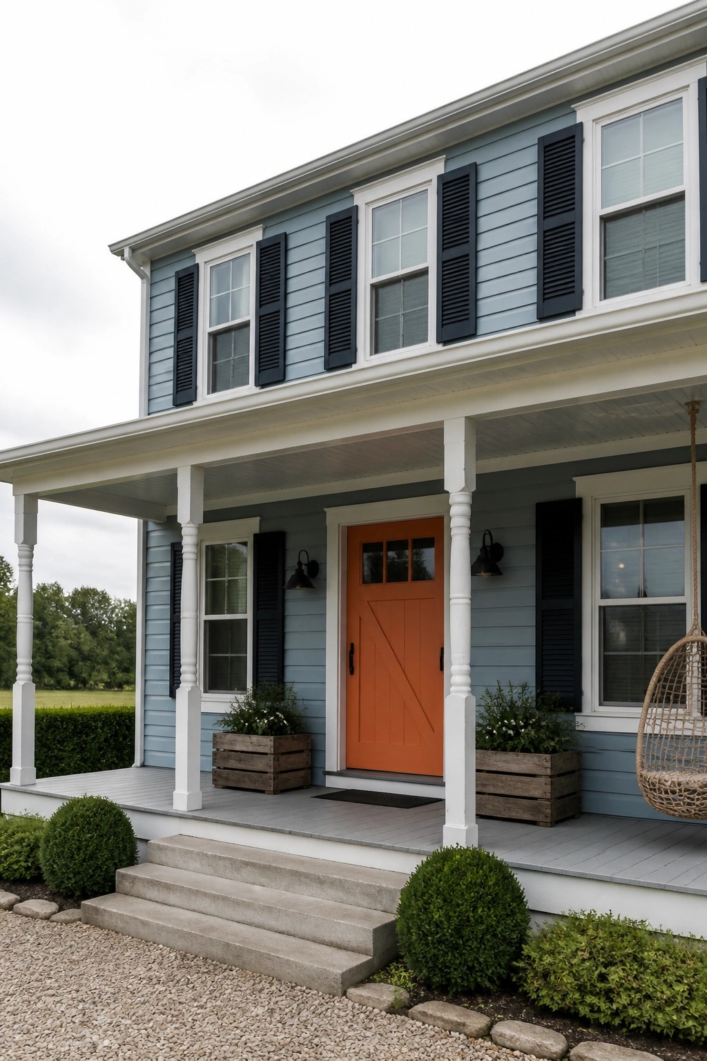 A two-story house with light blue siding, navy shutters, white trim, and an orange front door under a covered porch.