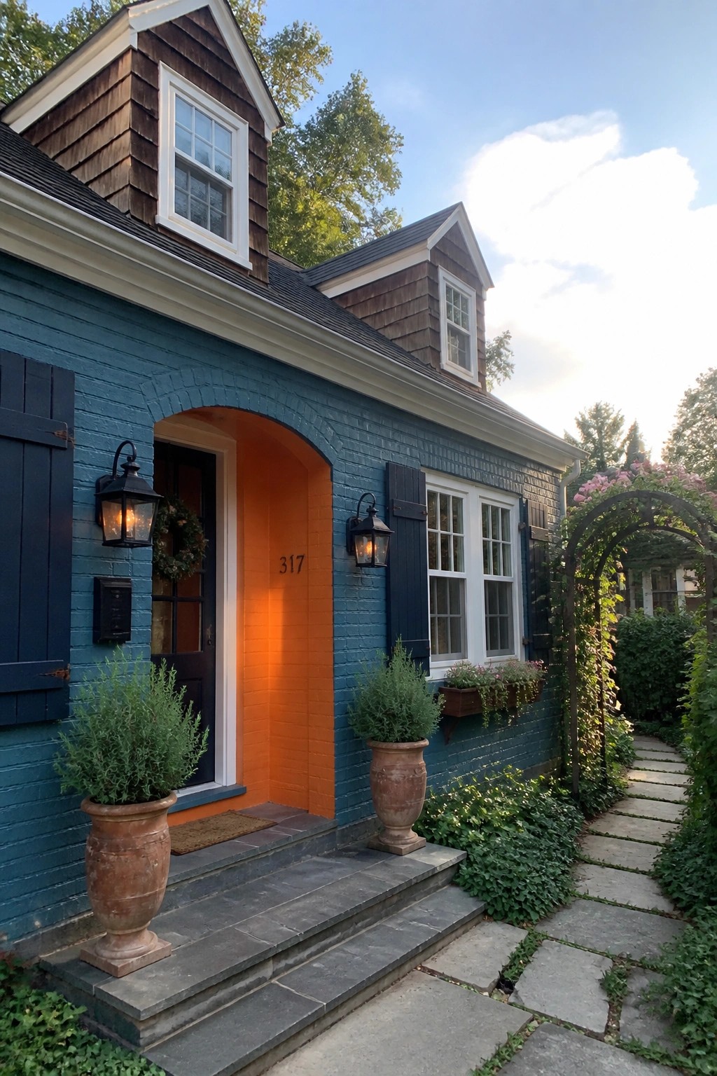 Blue house with orange arched doorway, potted plants, and stone pathway.