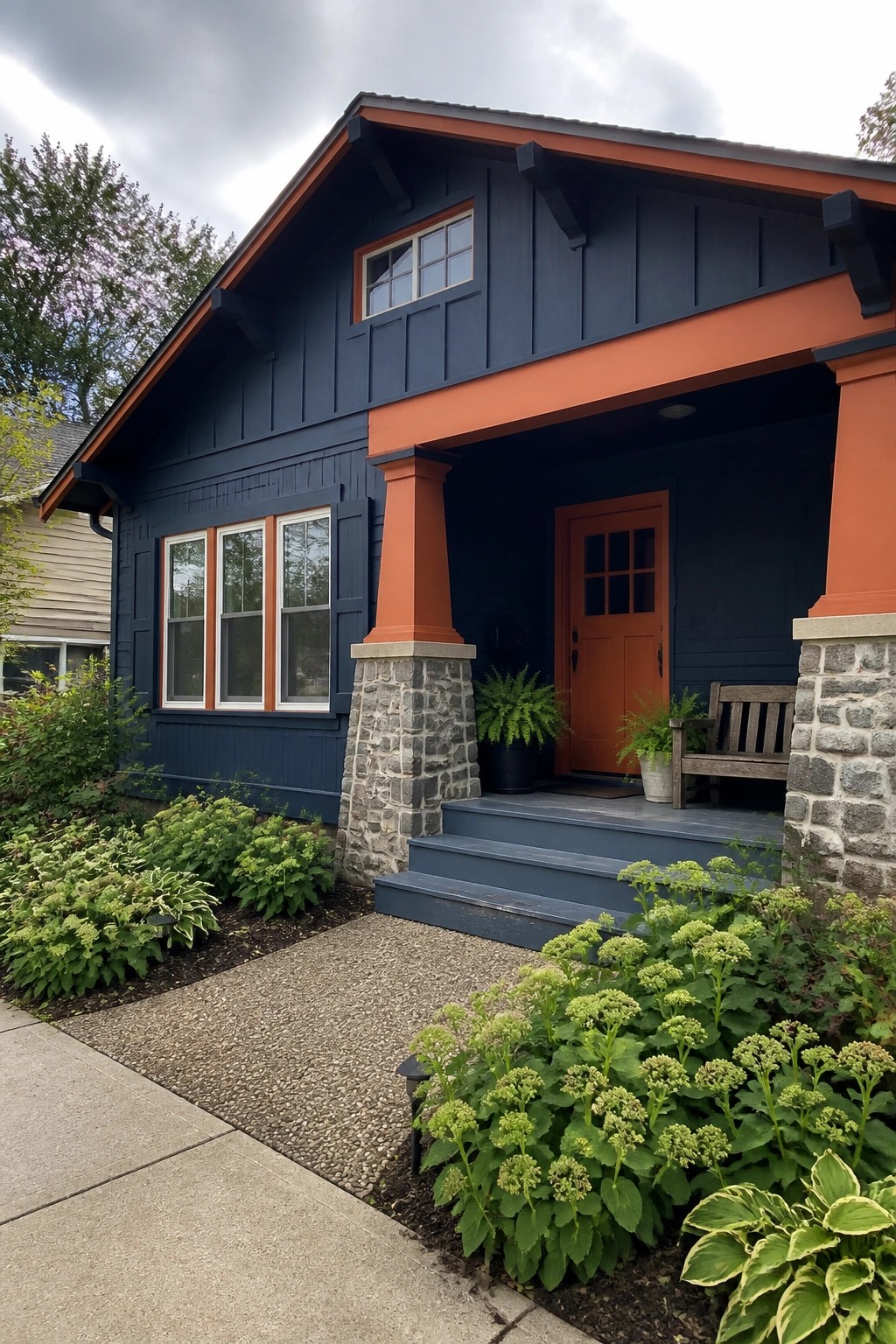 A navy blue house exterior with orange trim, orange door, and stone-based porch columns.