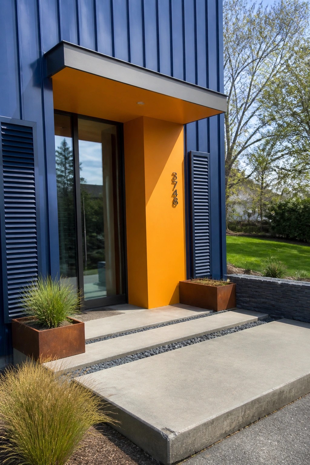 Modern blue house entrance with orange niche, metal planters, and concrete steps.