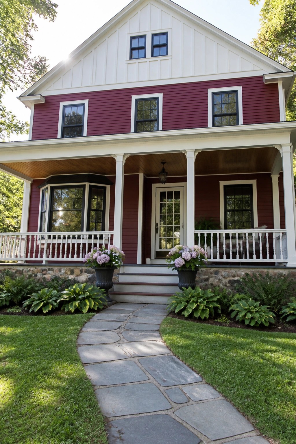 A two-story maroon house with white board-and-batten on the upper gable, white trim around windows and porch, a stone foundation, and a stone pathway leading to the front steps.