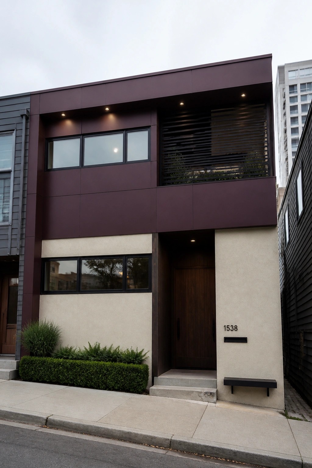 Modern two-story house exterior with deep burgundy upper facade, flat roof, concrete base, and wooden front door.