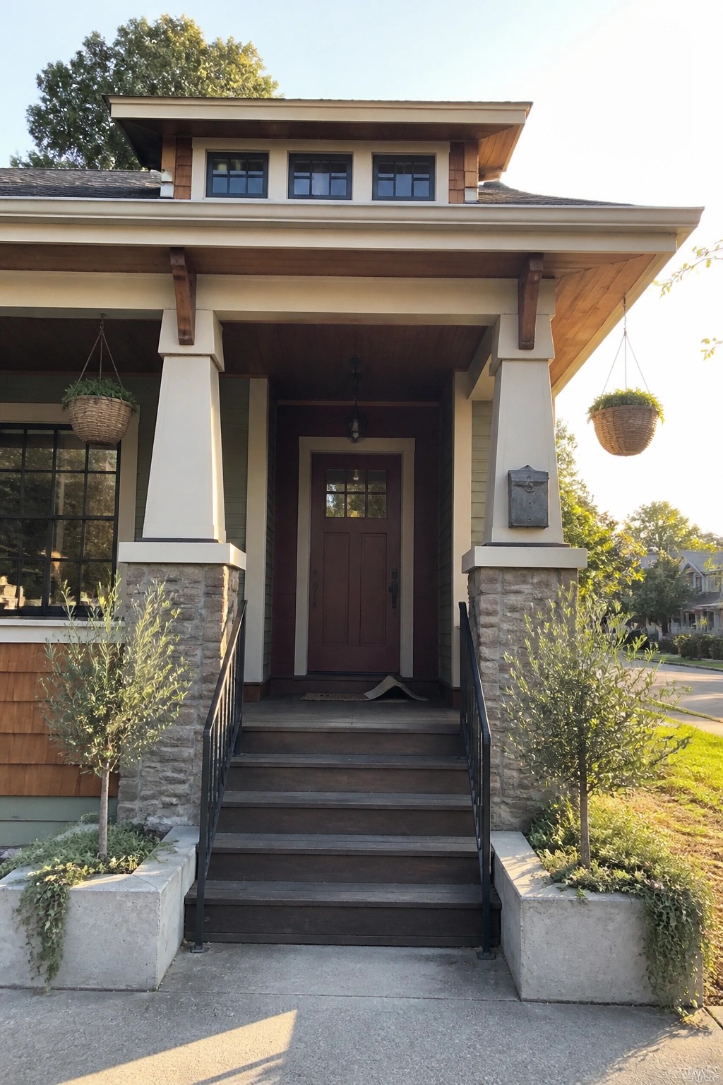 Covered front porch with brown door, stone pillars, hanging plants and wooden trim.