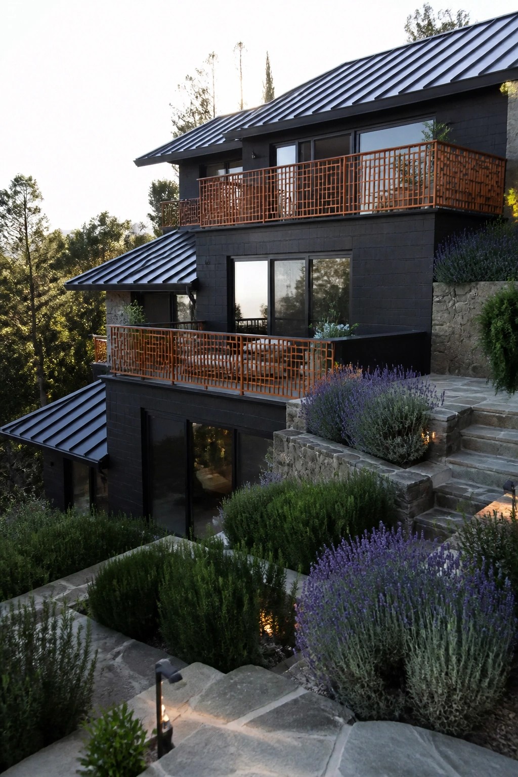Modern dark house with orange balconies amid purple lavender and stone steps.