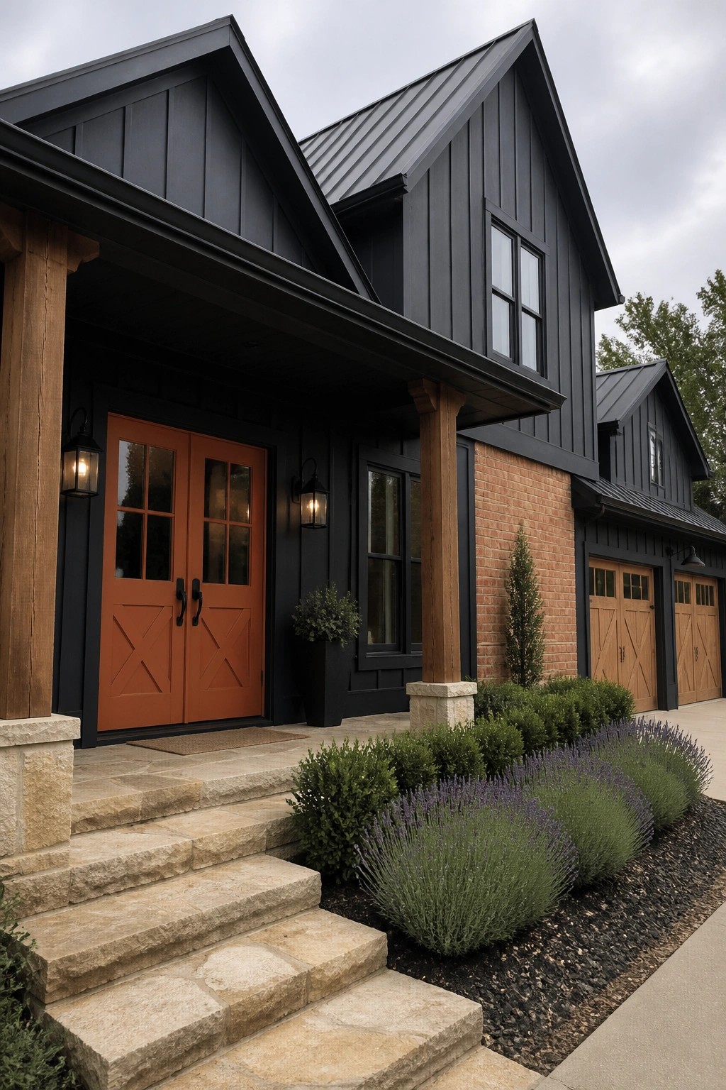 A two-story house with black siding, orange double front doors, a charcoal metal roof, stone steps, and landscaping in front.