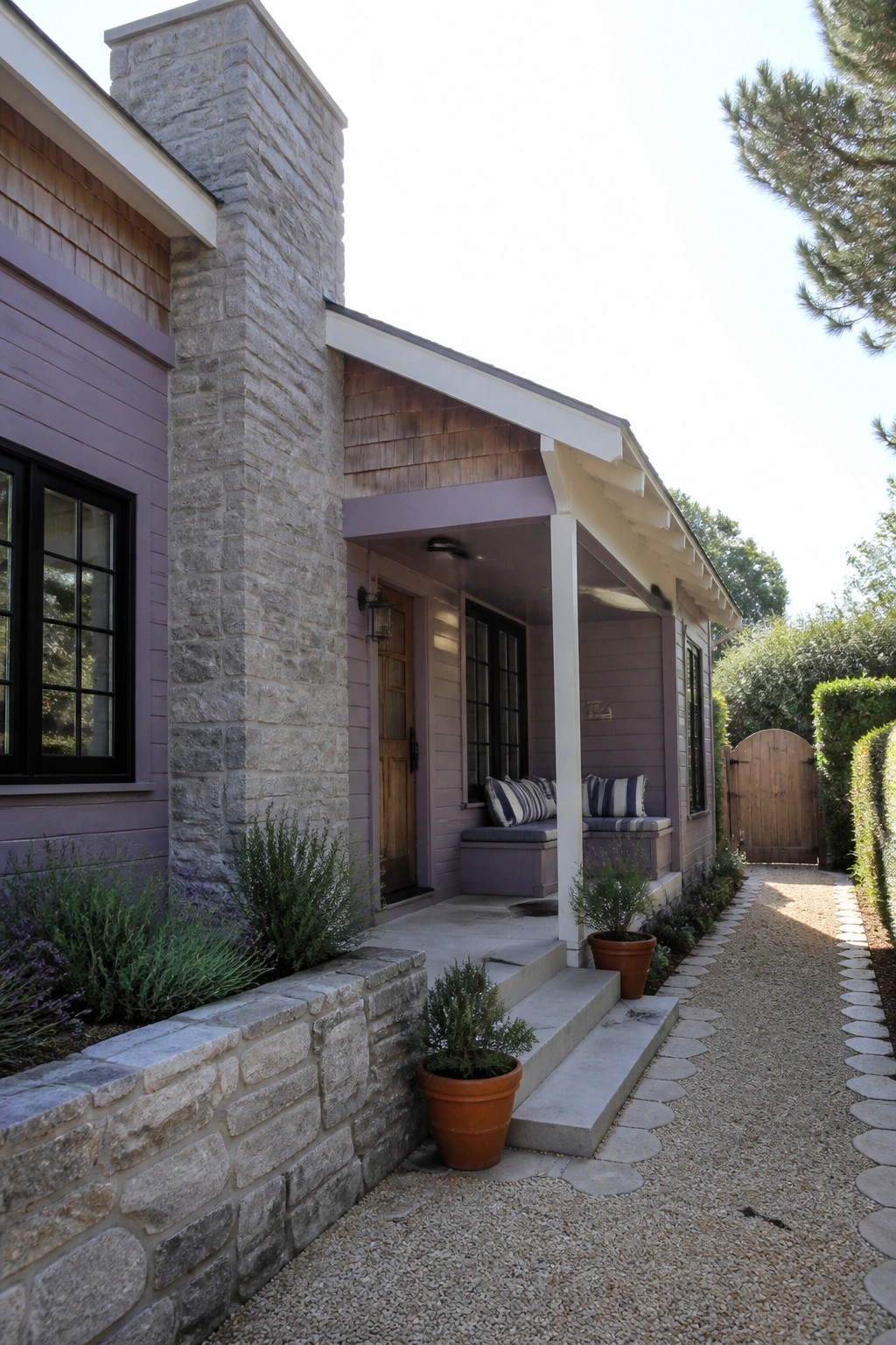 Purple house with stone chimney, covered porch, built-in seating, and gravel path