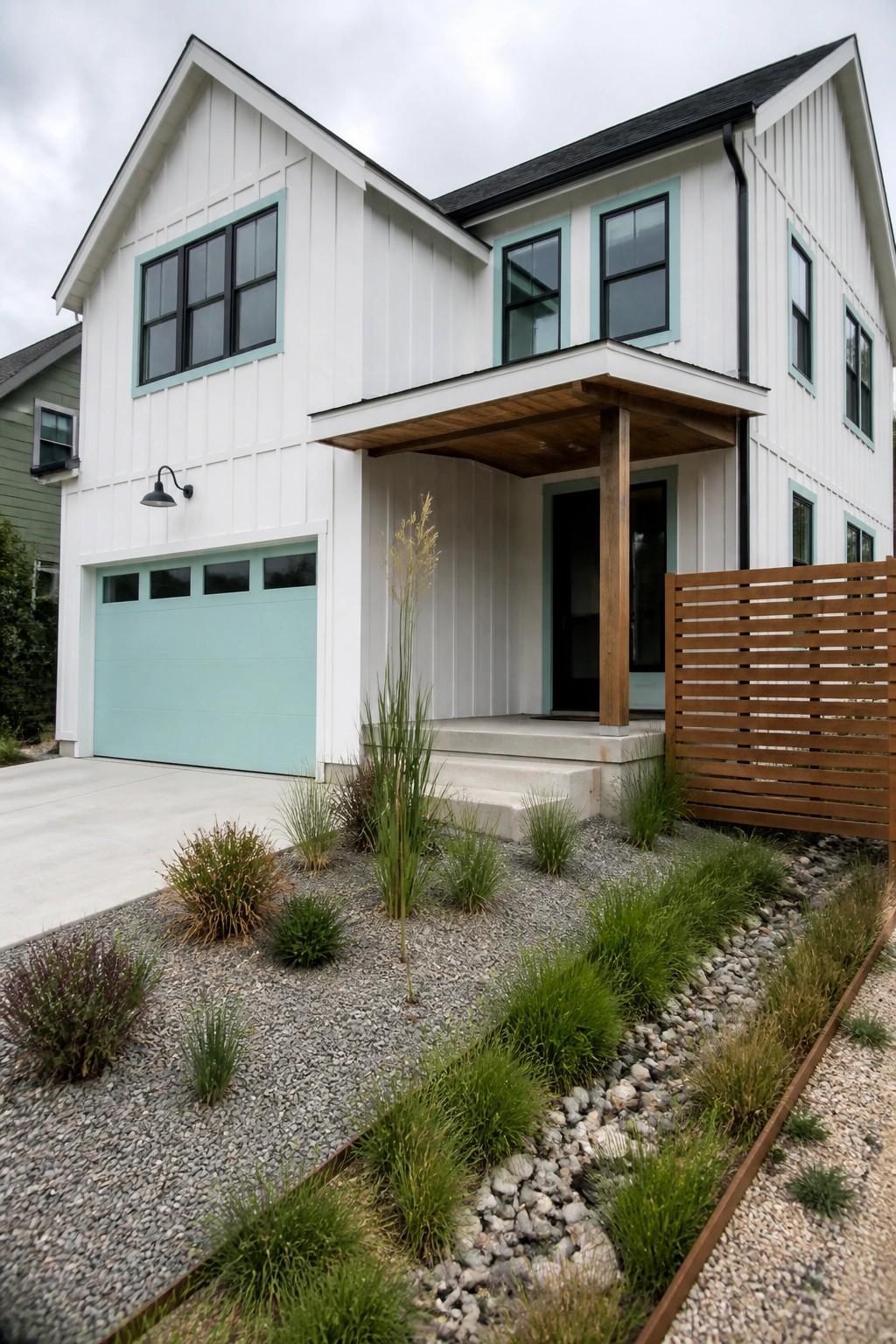 A two-story house with white board-and-batten siding features light teal garage door and window trim along with a wooden front porch.