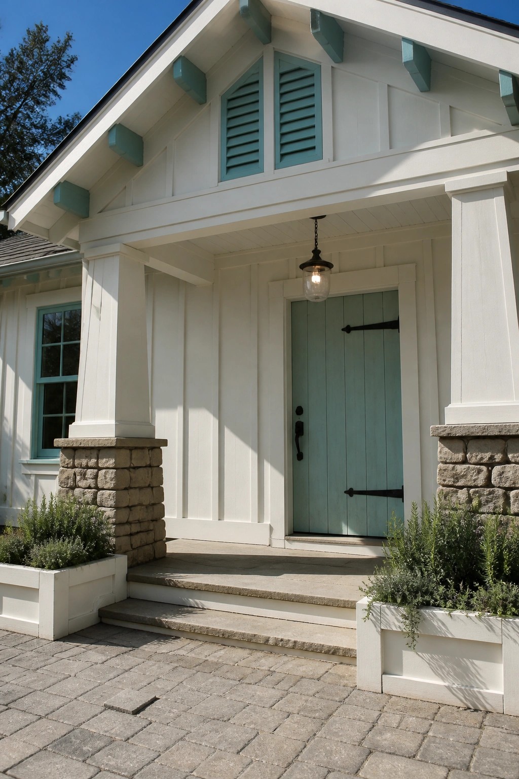 A white board-and-batten house with a light teal front door, matching teal shutters above the porch, and stone pillars supporting the entry.