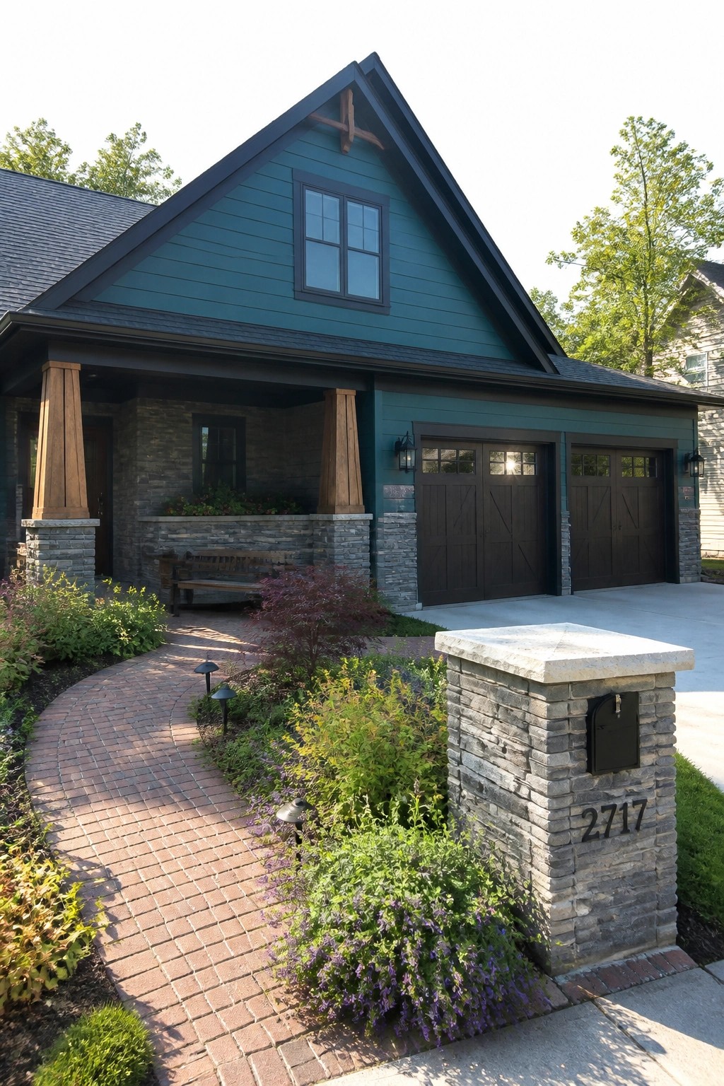 Teal house with dark trim, double garage doors, brick path, and stone mailbox pillar.