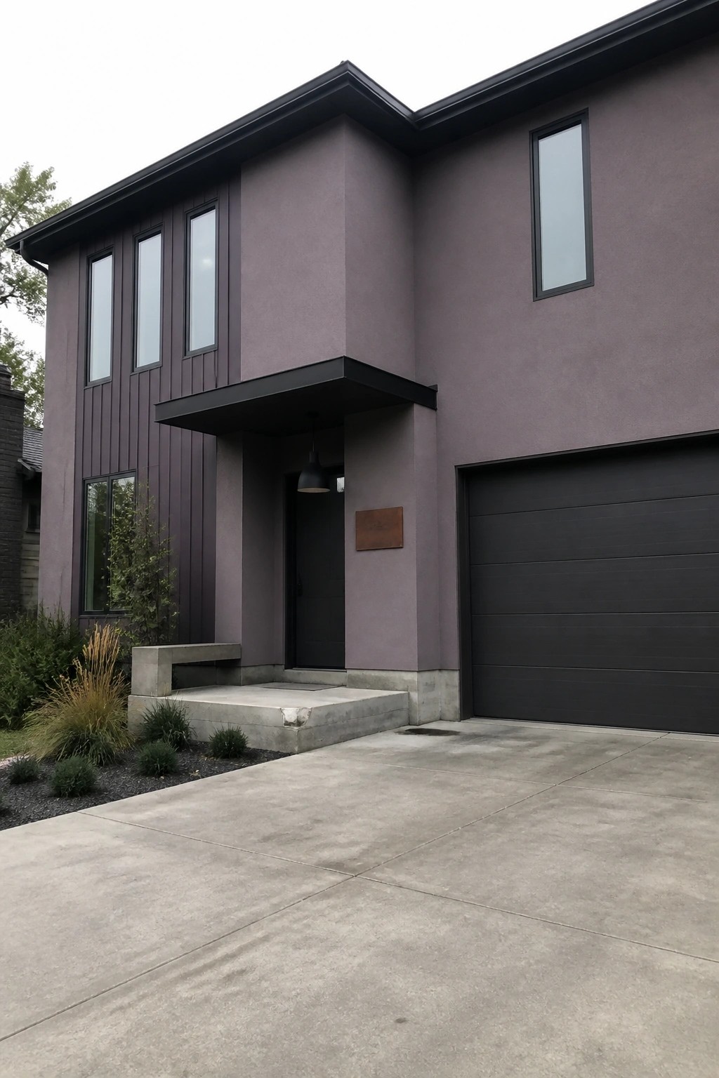 Modern two-story home with purple siding, dark garage door, and concrete driveway.