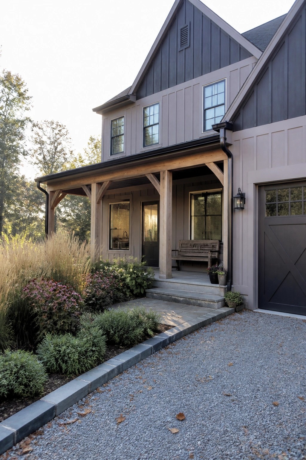 Modern farmhouse with dark siding, wooden porch, bench, and gravel driveway.