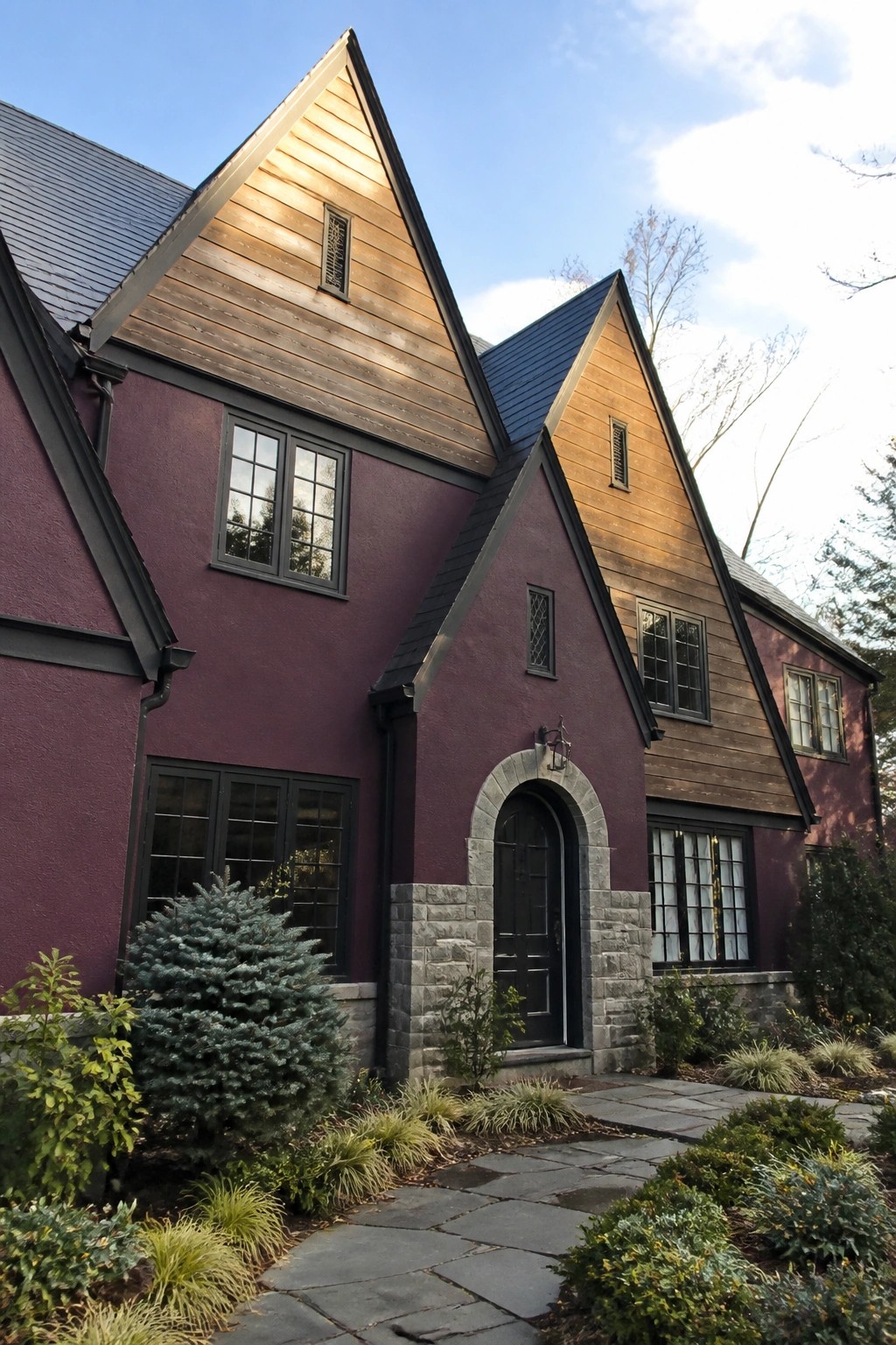 Purple house with wooden gables, stone arched entry, and garden path.